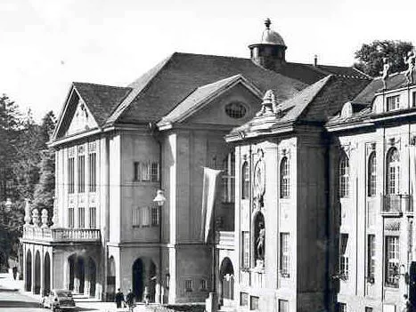 Black-and-white exterior view of the Mozarteum building showing its classical facade with arched portico, central dome, and statues in niches