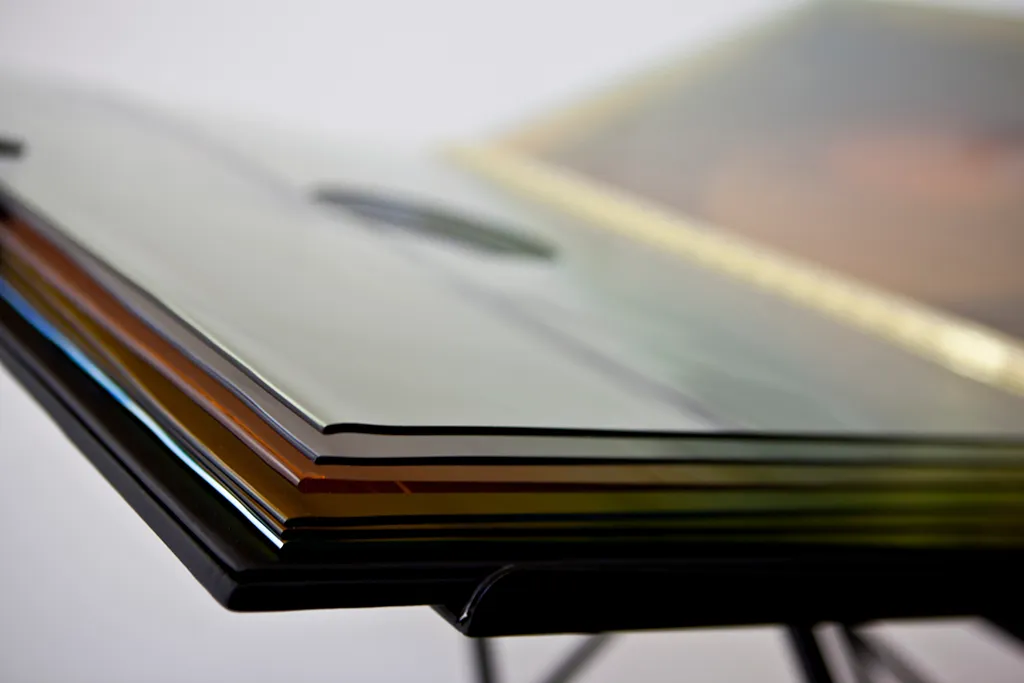 pila de libros de artista con páginas coloridas sobre un soporte negro