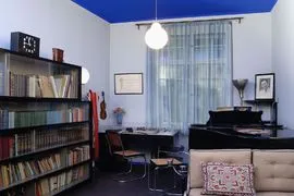 pokój z niebieskim sufitem, regałem, pianinem i sofą