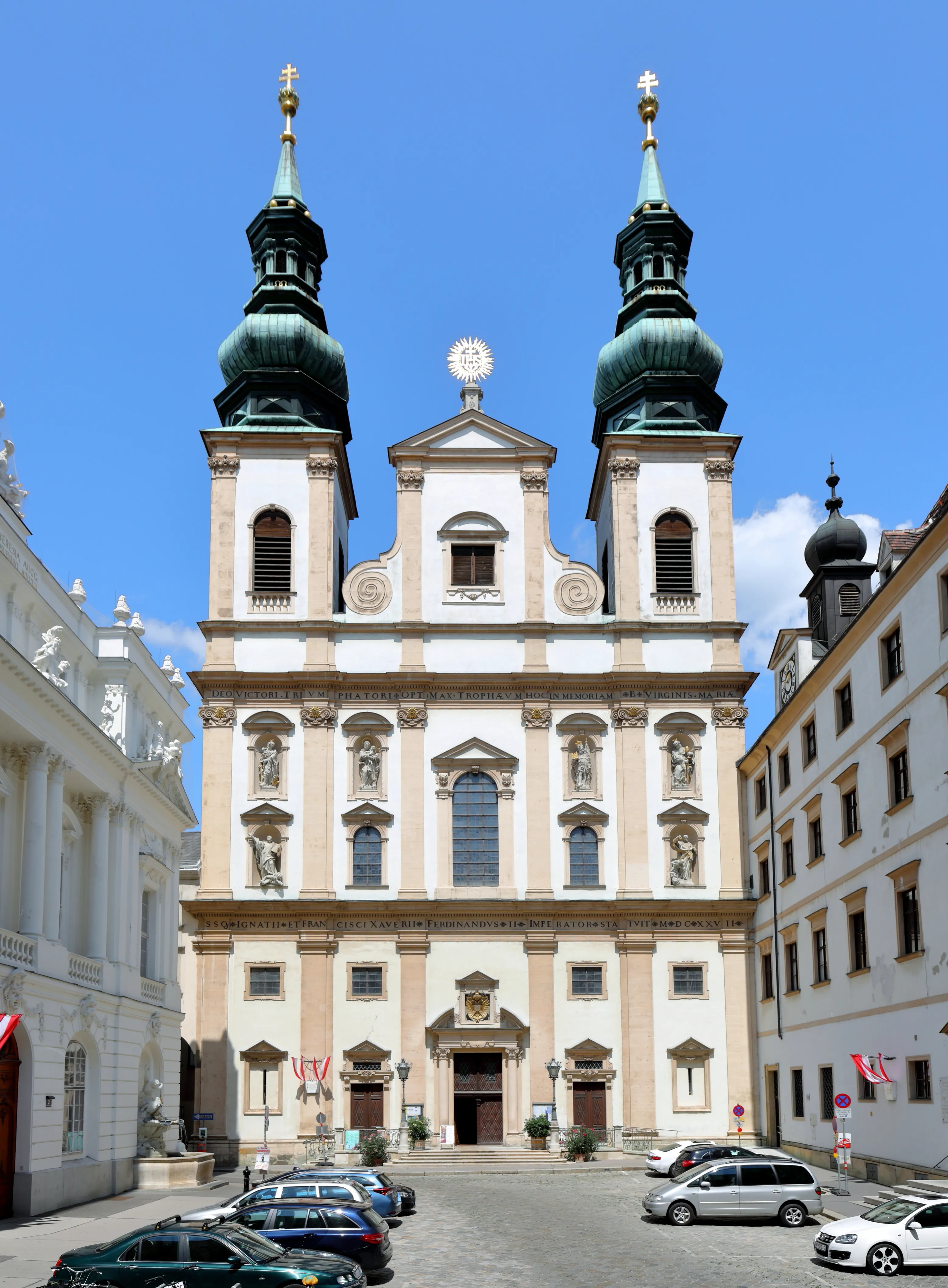 Iglesia barroca con campanarios gemelos verdes y fachada ornamentada bajo un cielo azul