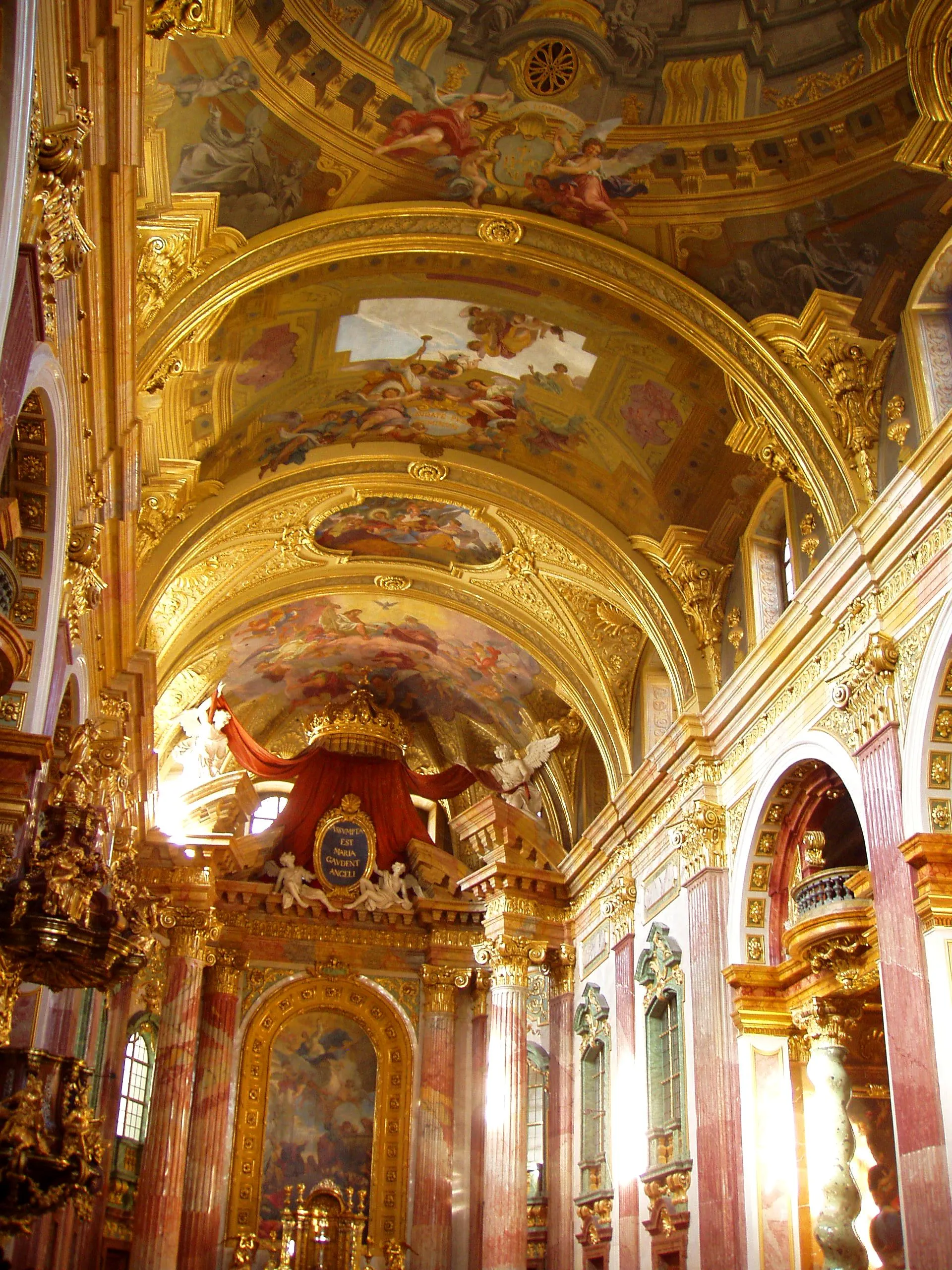 Ornato interior barroco de la Iglesia Jesuita con arcos dorados, techos pintados y un altar central
