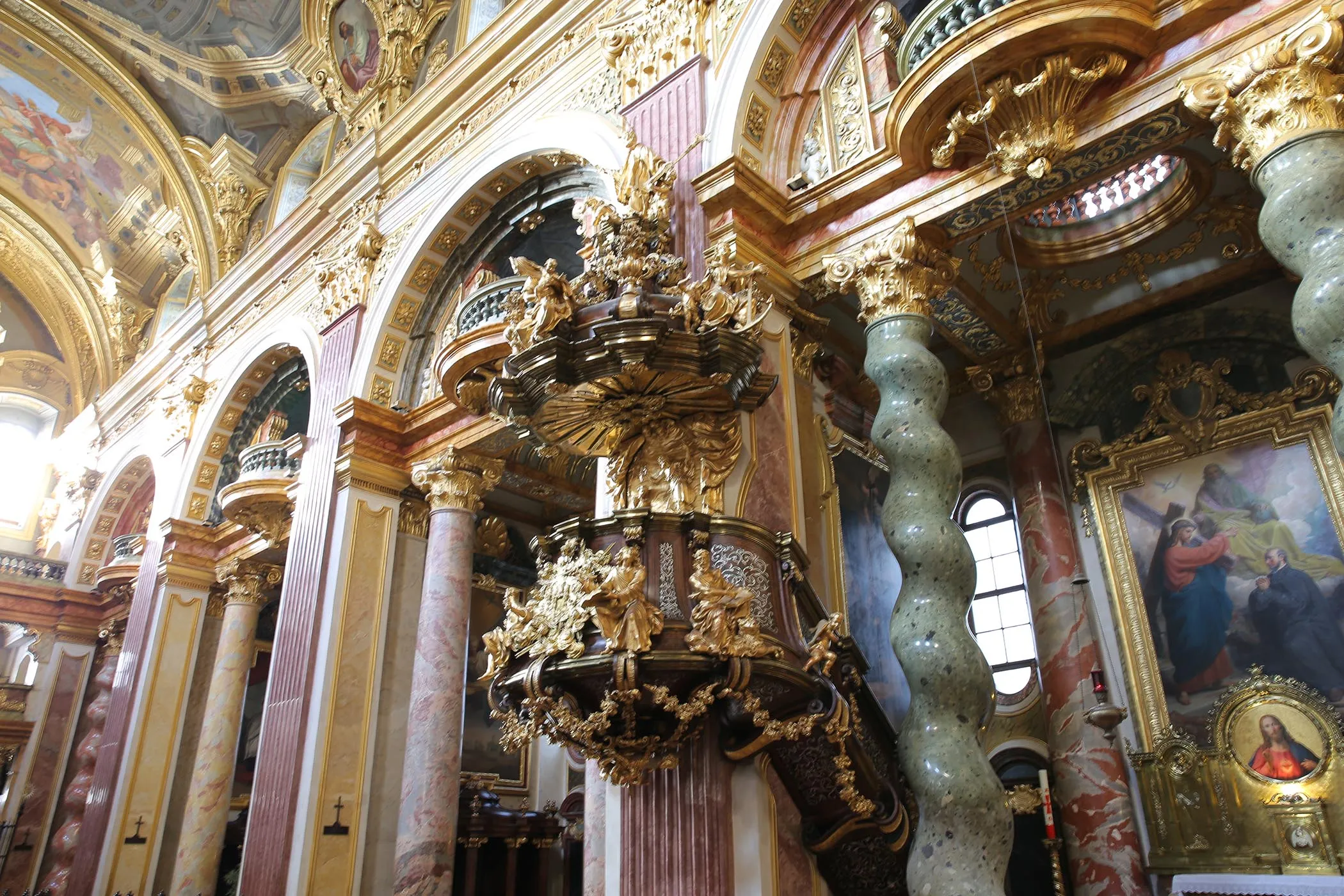 Interieur van de Jezuïetenkerk met sierlijke gouden details, marmeren zuilen en een grote preekstoel.