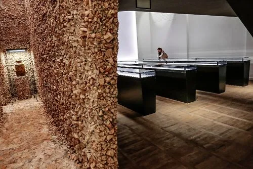 Exhibition space with a textured stone wall and display cases