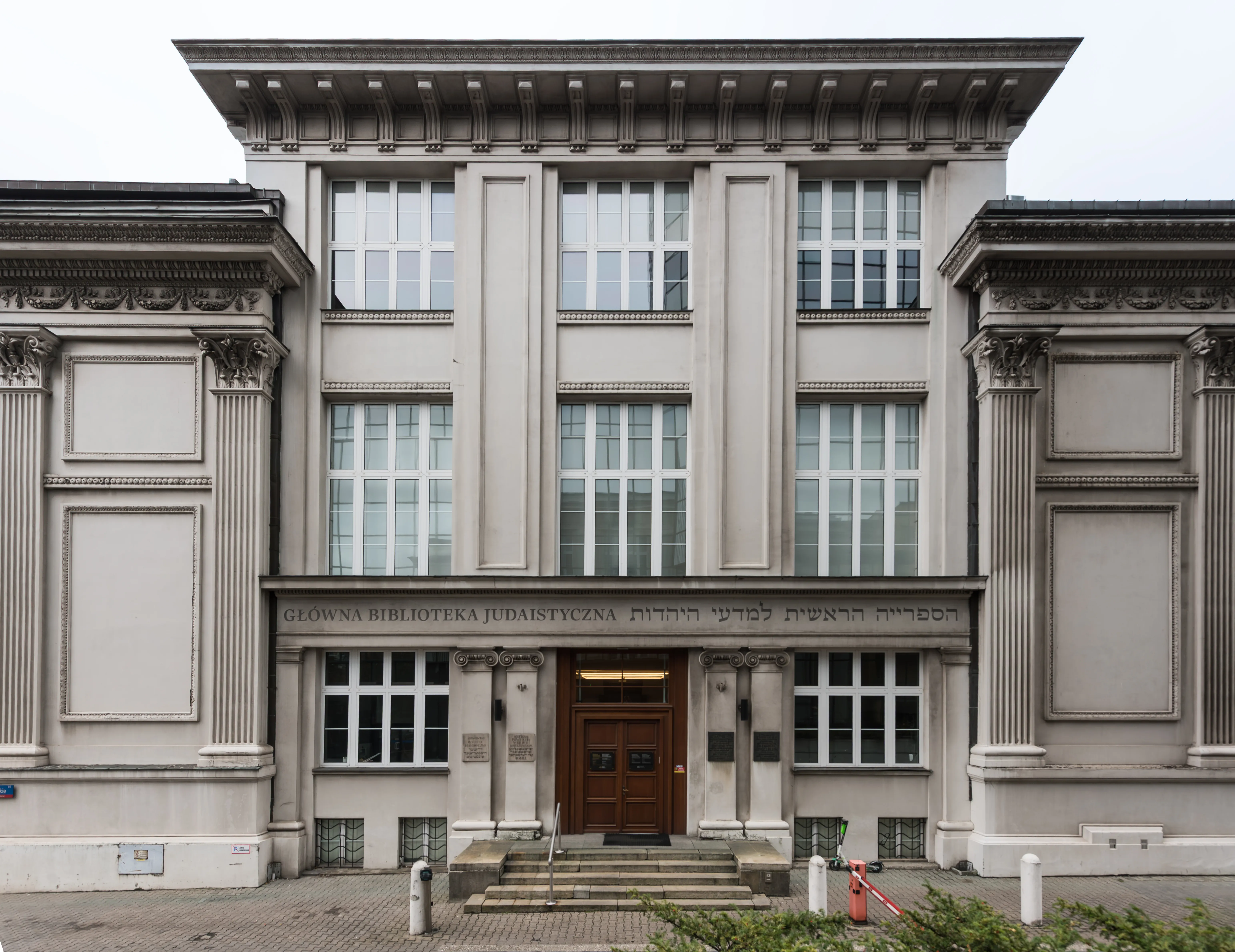 Neoclassical building with columns, large windows, and a central entrance with a wooden door and steps
