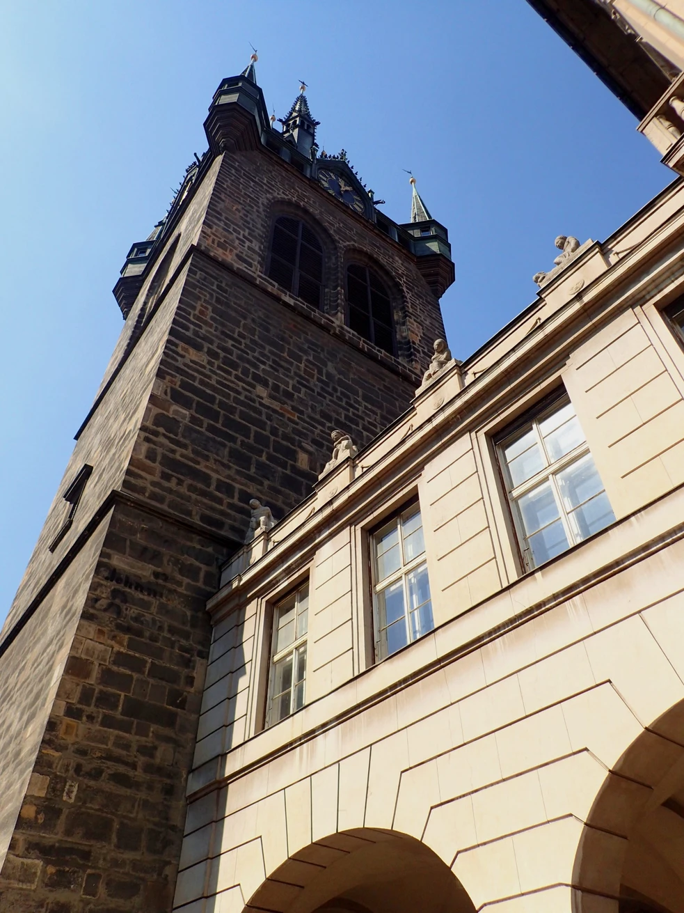 Gotische belfort met donkere stenen muren en torenspitsen onder een blauwe hemel