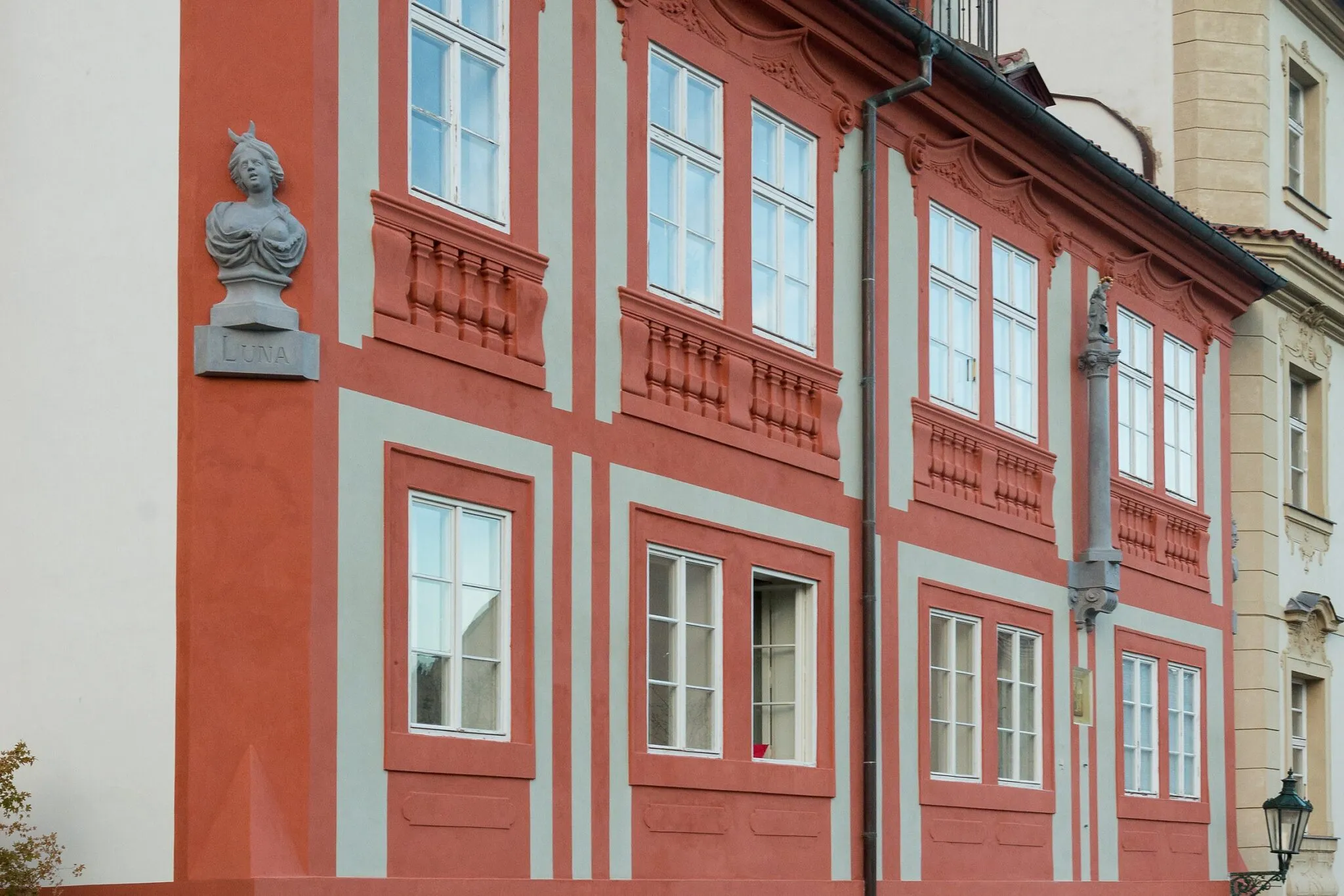 Czerwono-biała fasada budynku z popiersiem mężczyzny na postumencie