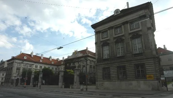 classical stone building with red-tiled roofs and tram lines in front