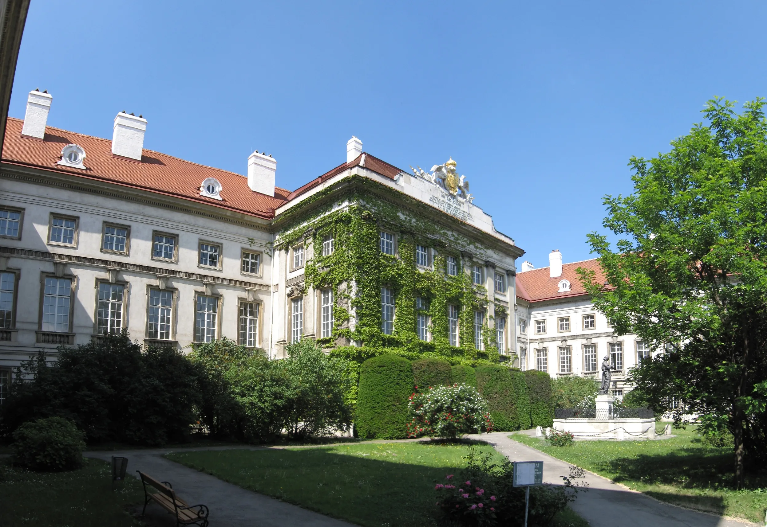 classical building with red roof and ivy-covered walls under blue sky