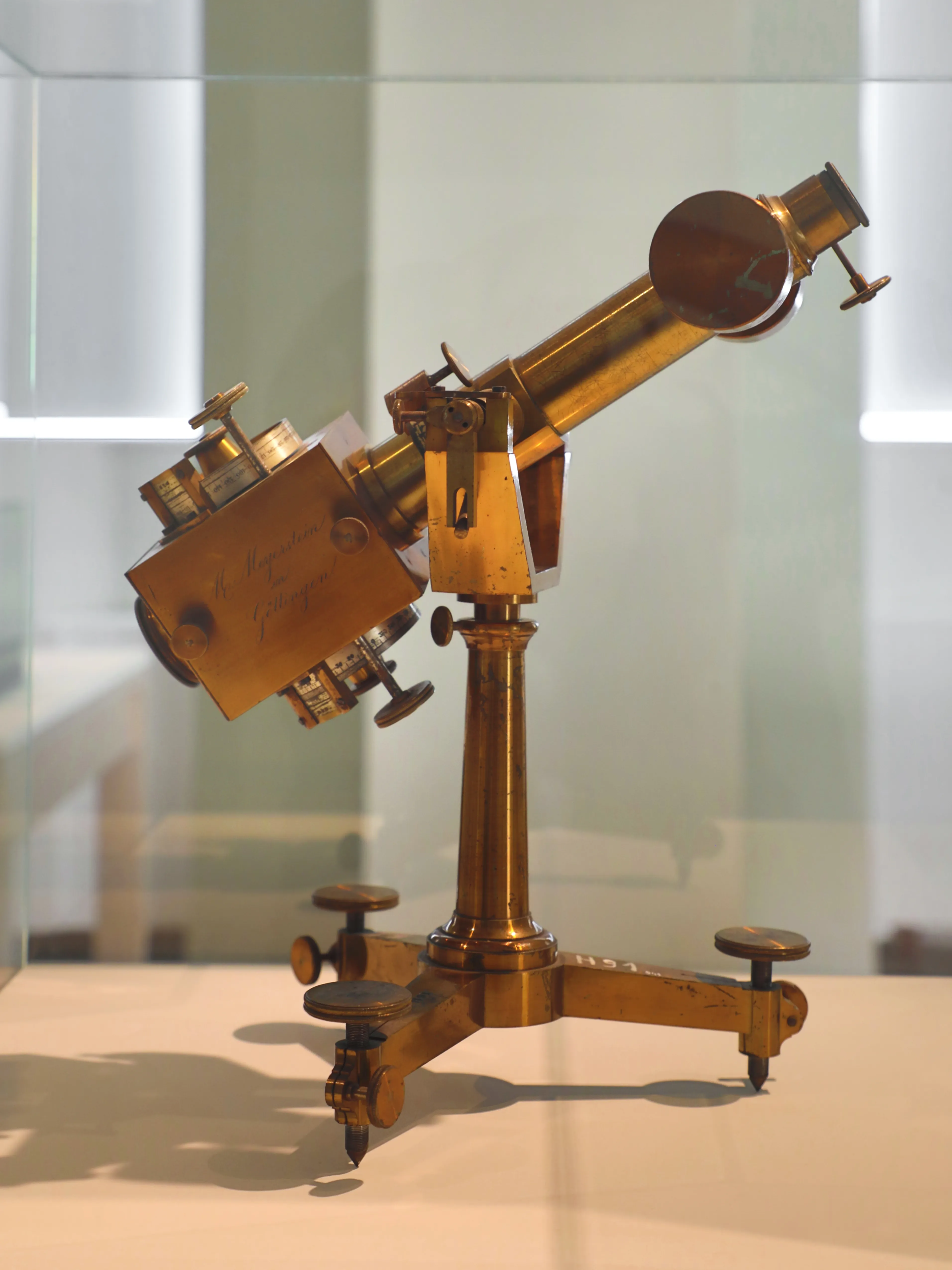 antique brass scientific instrument on a stand in a display case