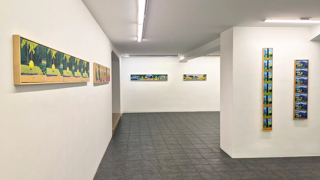 Gallery interior with white walls displaying framed paintings and artworks, gray tile floor, and track lighting