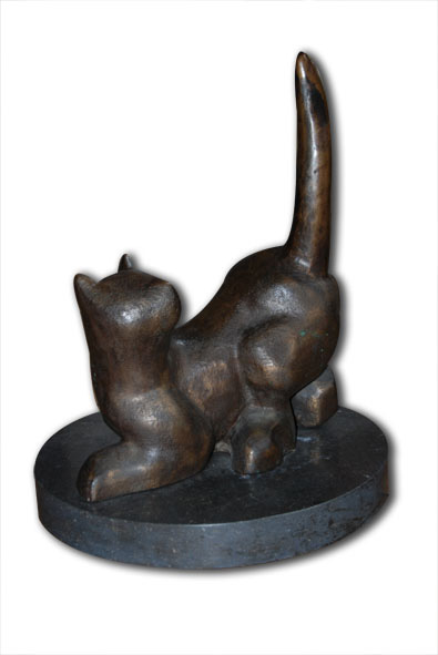 Bronzen sculptuur van een hurkende kat met opgetrokken staart op een cirkelvormige donkere sokkel tegen een witte achtergrond