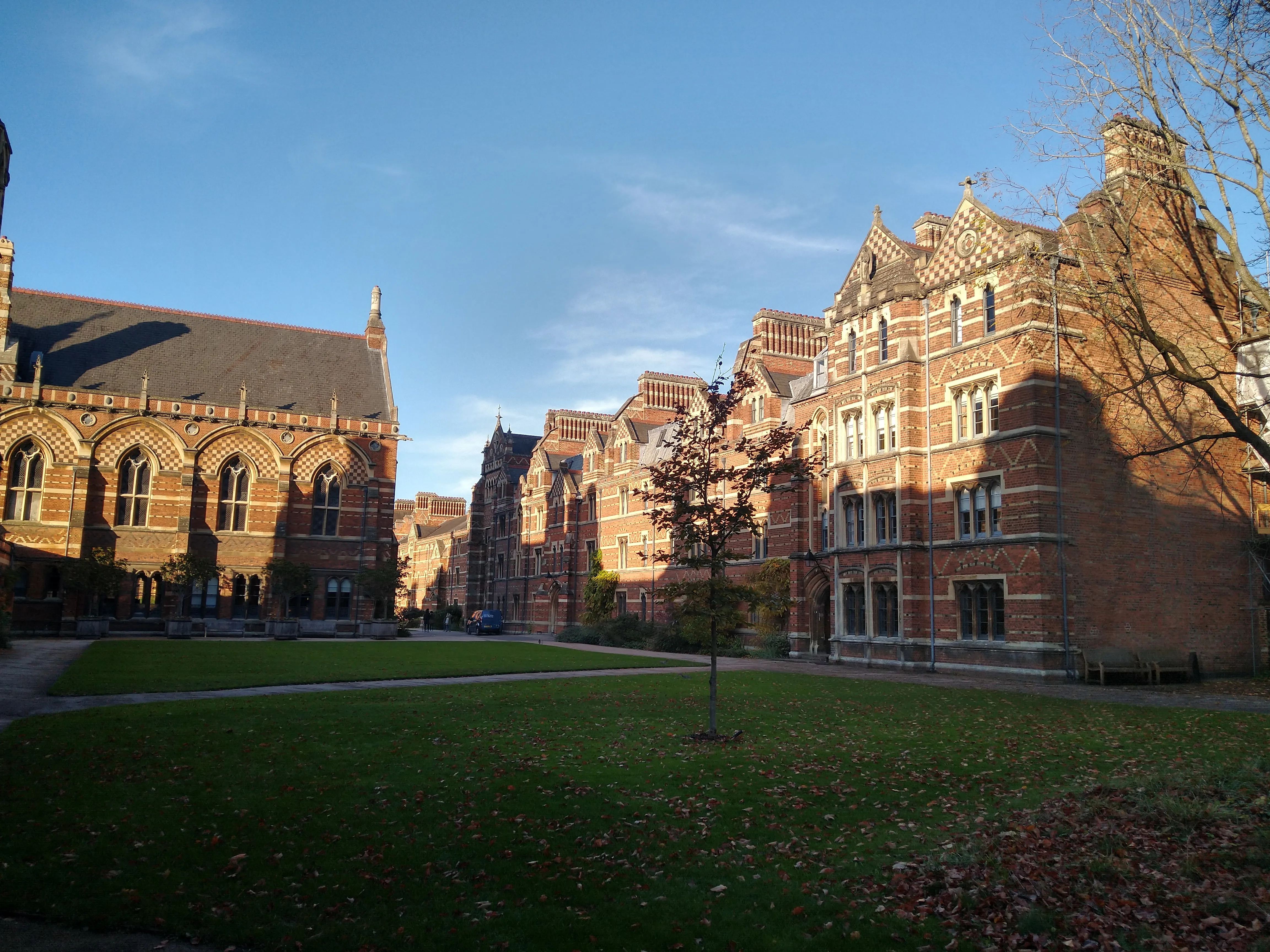 Pusey Quad op Keble College met victoriaanse polychrome bakstenen gebouwen met gotische ramen rondom een groen gazon onder een blauwe lucht