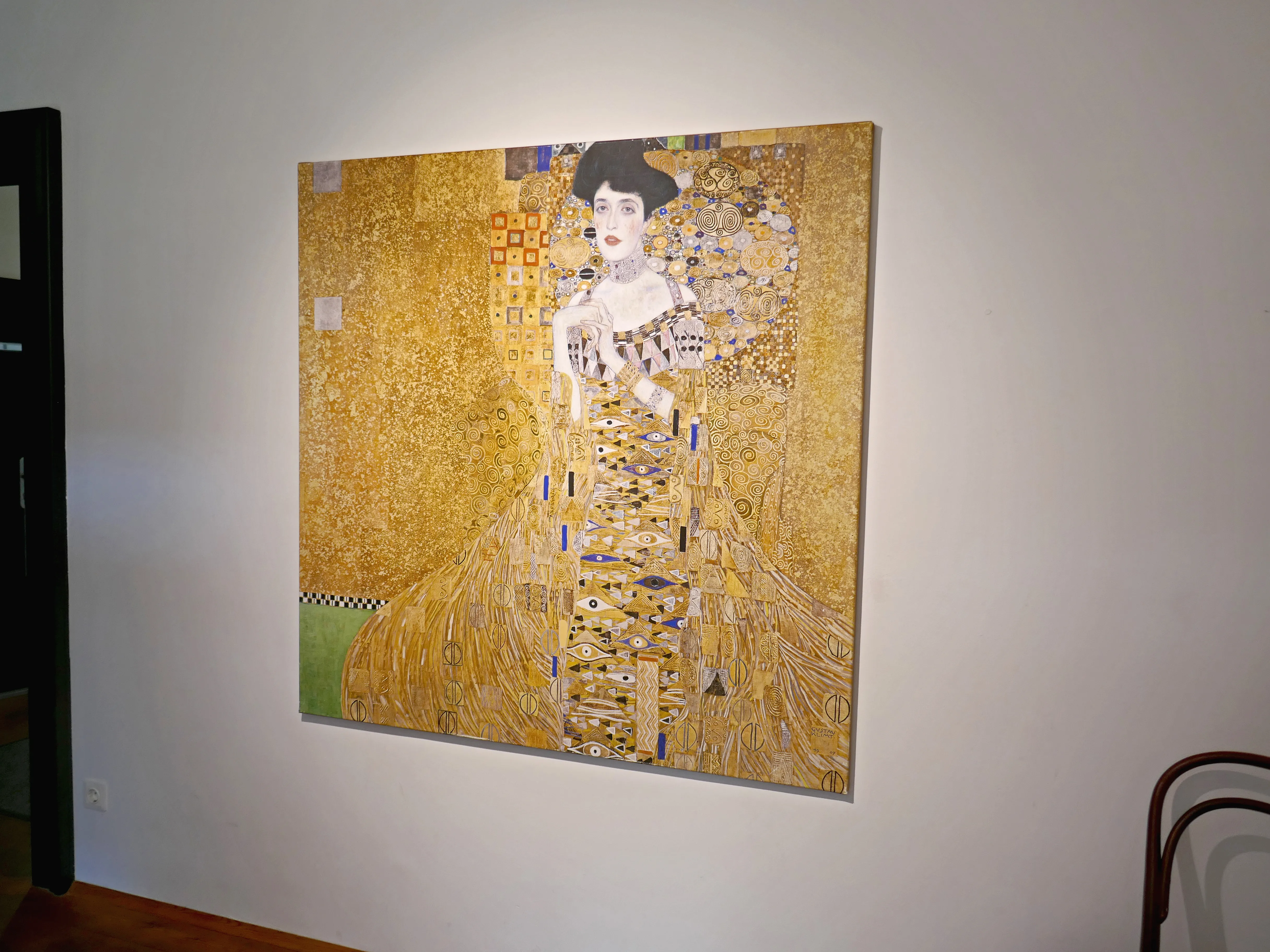 A large painting of a woman in a gold-embellished dress hanging on a white wall