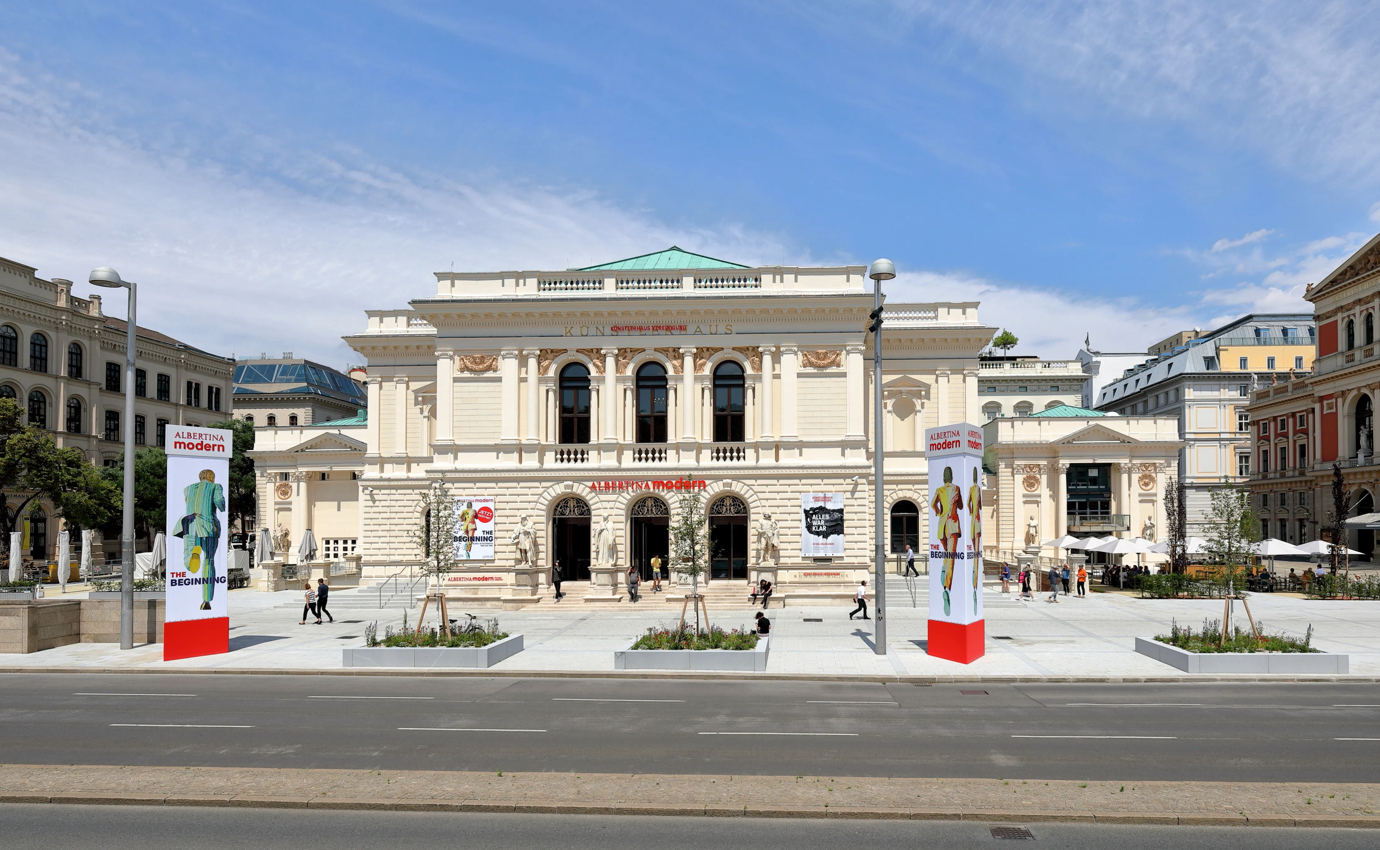 Het Künstlerhaus Wien gebouw met een klassieke gevel, boogramen en spandoeken ervoor op een zonnige dag