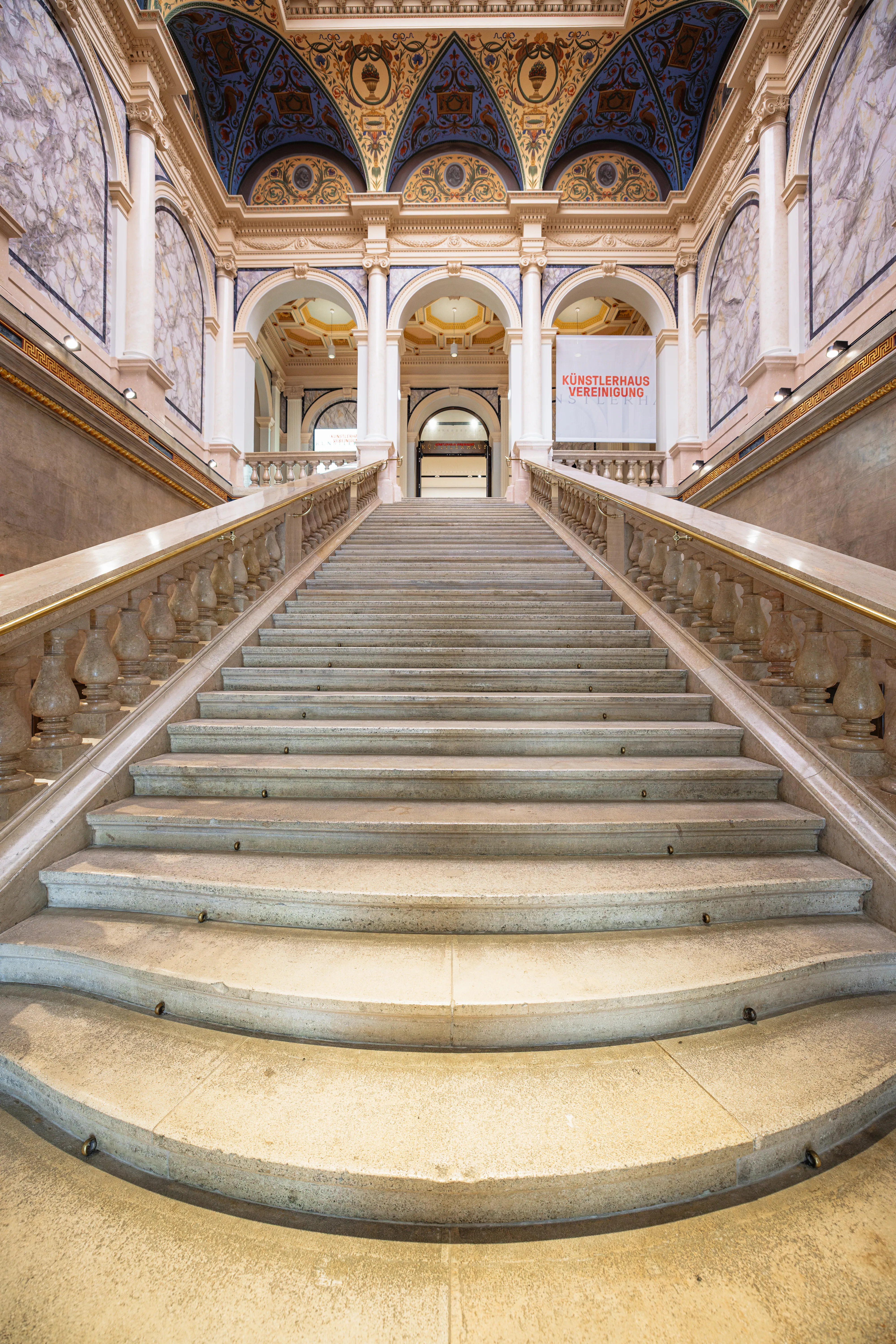 Grote trap in Künstlerhaus Wien met sierlijke blauw-gouden plafondfresco's en marmeren balustrades