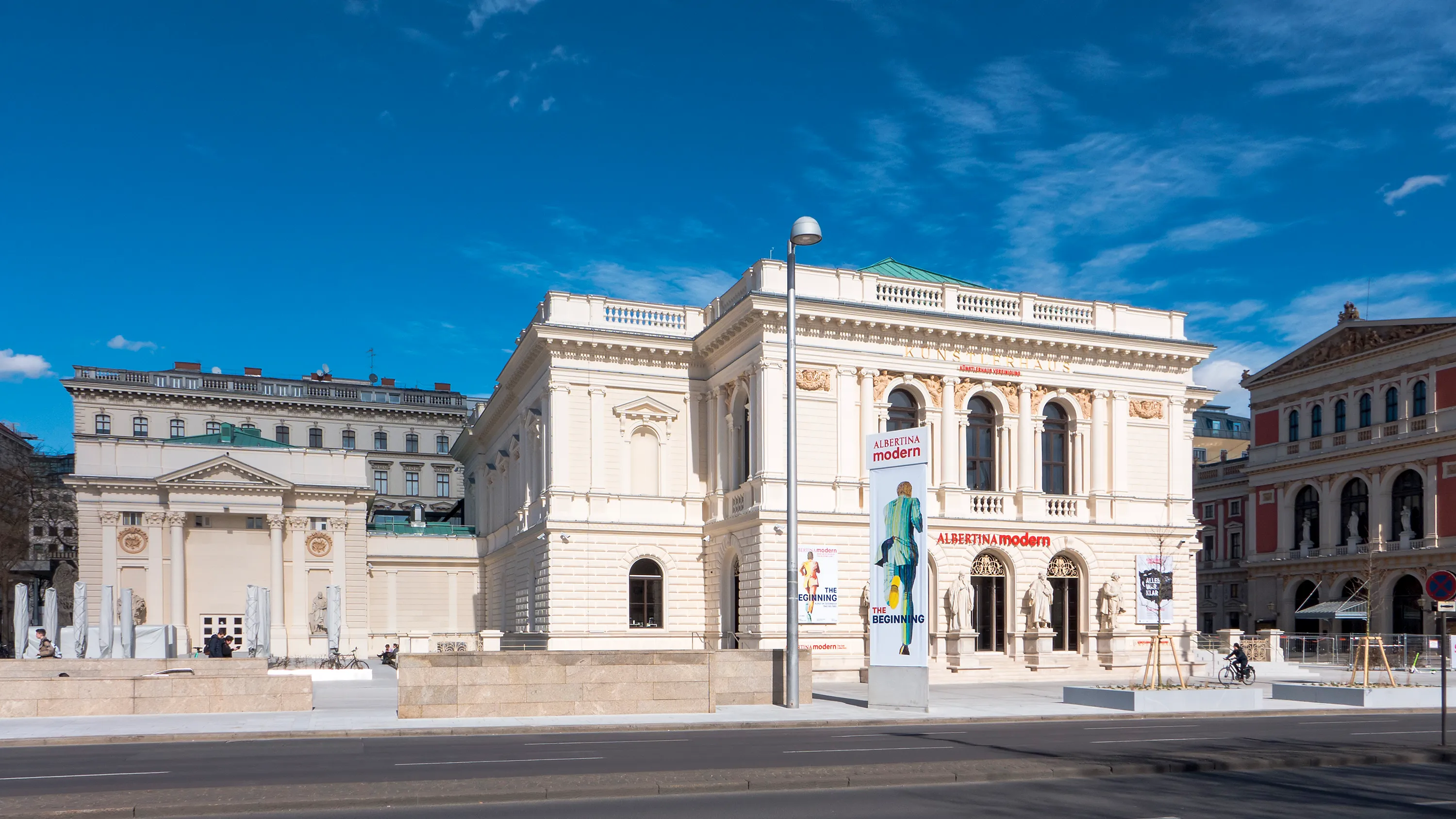 Neoclassicistisch gebouw met witte gevel, boogramen en een blauwe lucht als achtergrond