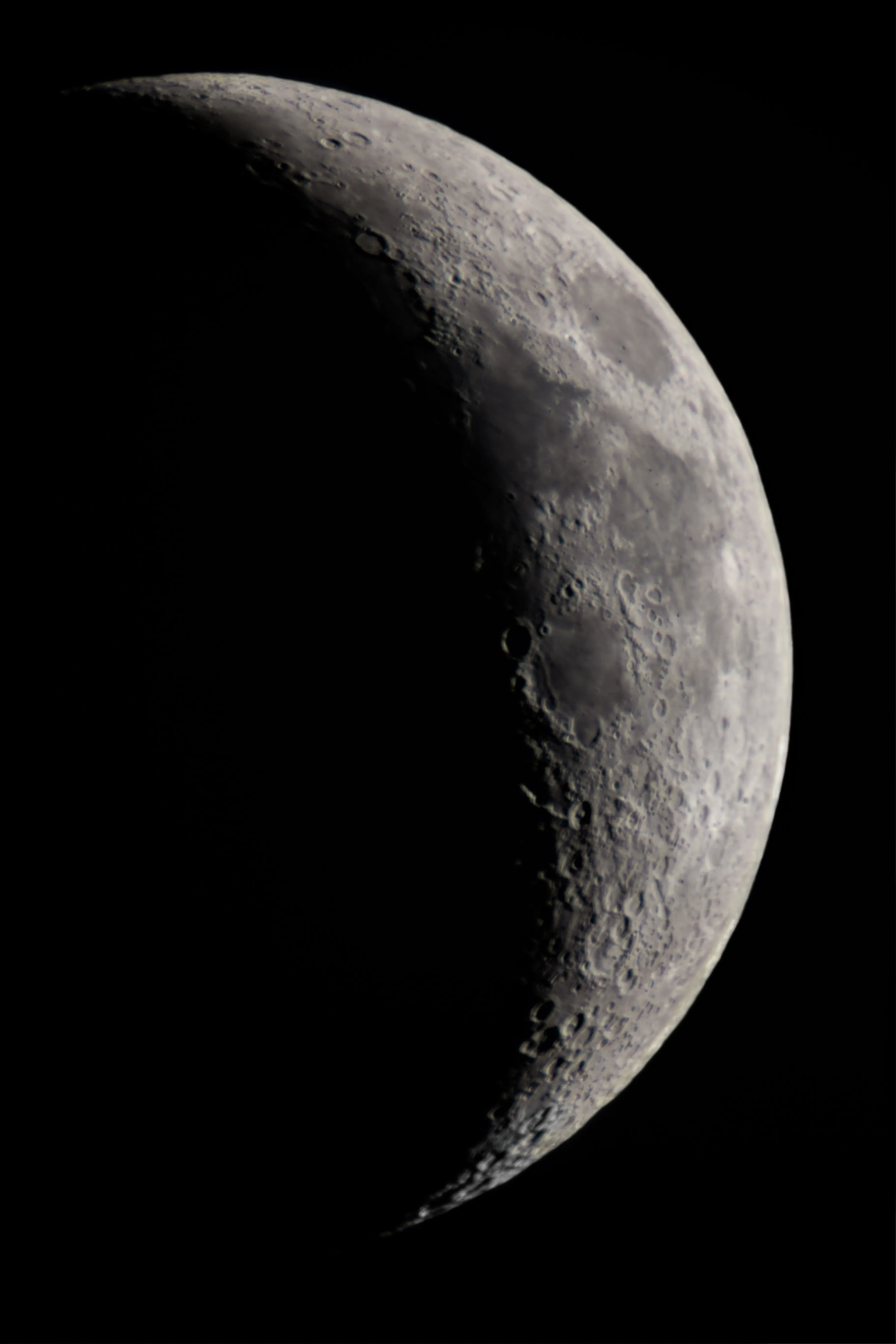 Una fotografía en blanco y negro de alto contraste de la Luna que muestra cráteres y mares detallados a lo largo de la línea del terminador sobre un fondo negro.
