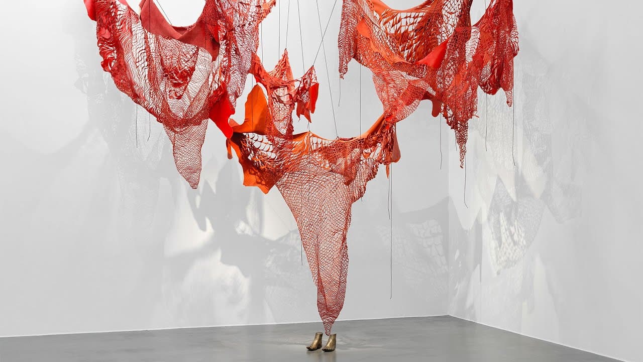 Red textile sculpture hanging from the ceiling in a gallery