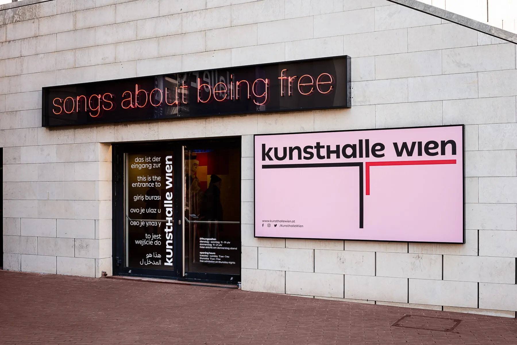 Kunsthalle Wien entrance with a pink sign and a digital display showing 'songs about being free'