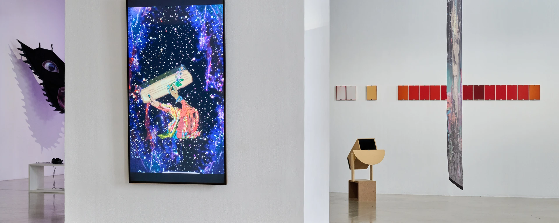 Galeria sztuki współczesnej z cyfrowym dziełem sztuki na ekranie, rzędem kolorowych paneli i wysoką rzeźbą.