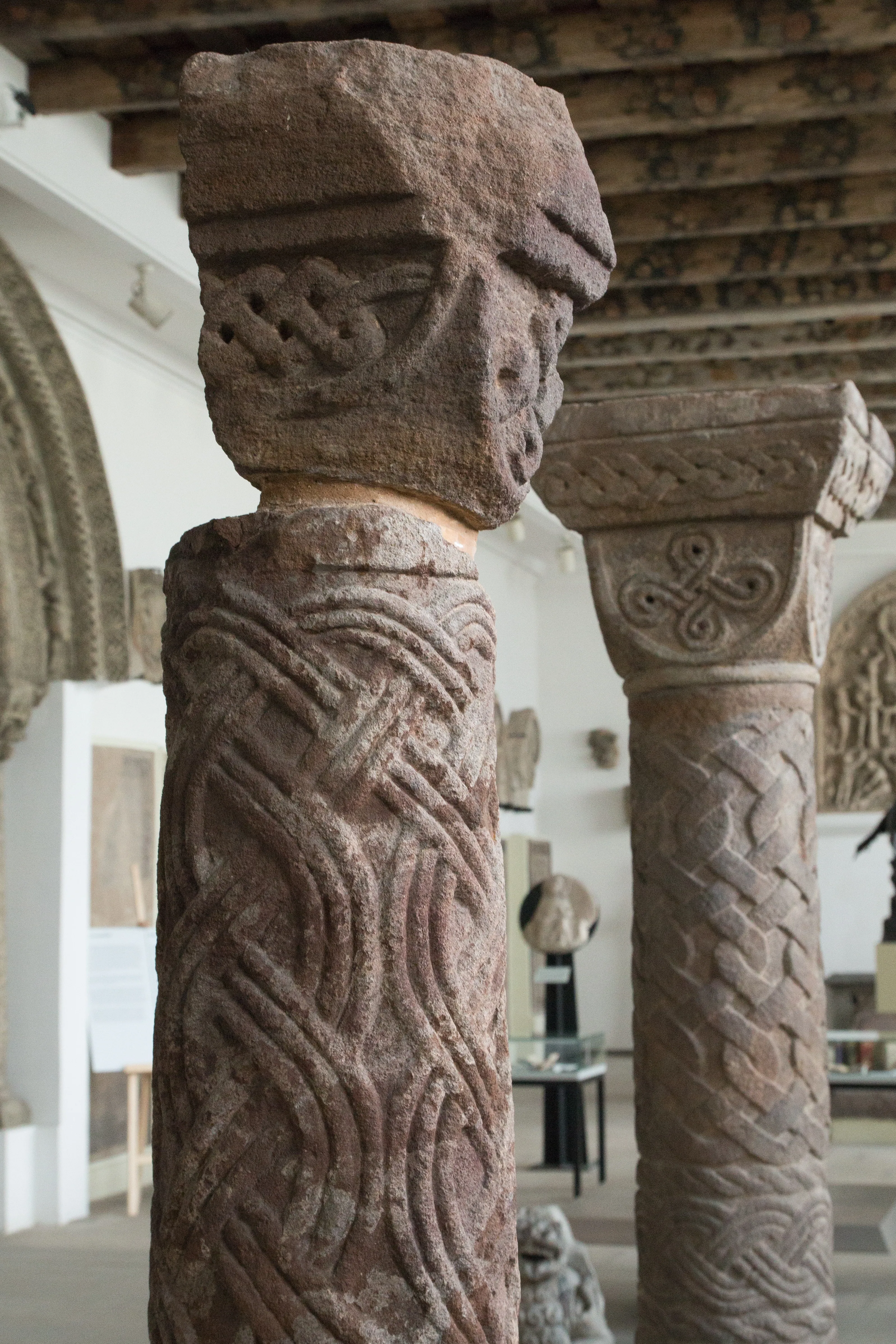 Close-up van uitgesneden stenen pilaren met Keltische knoopmotieven in een museumgalerij