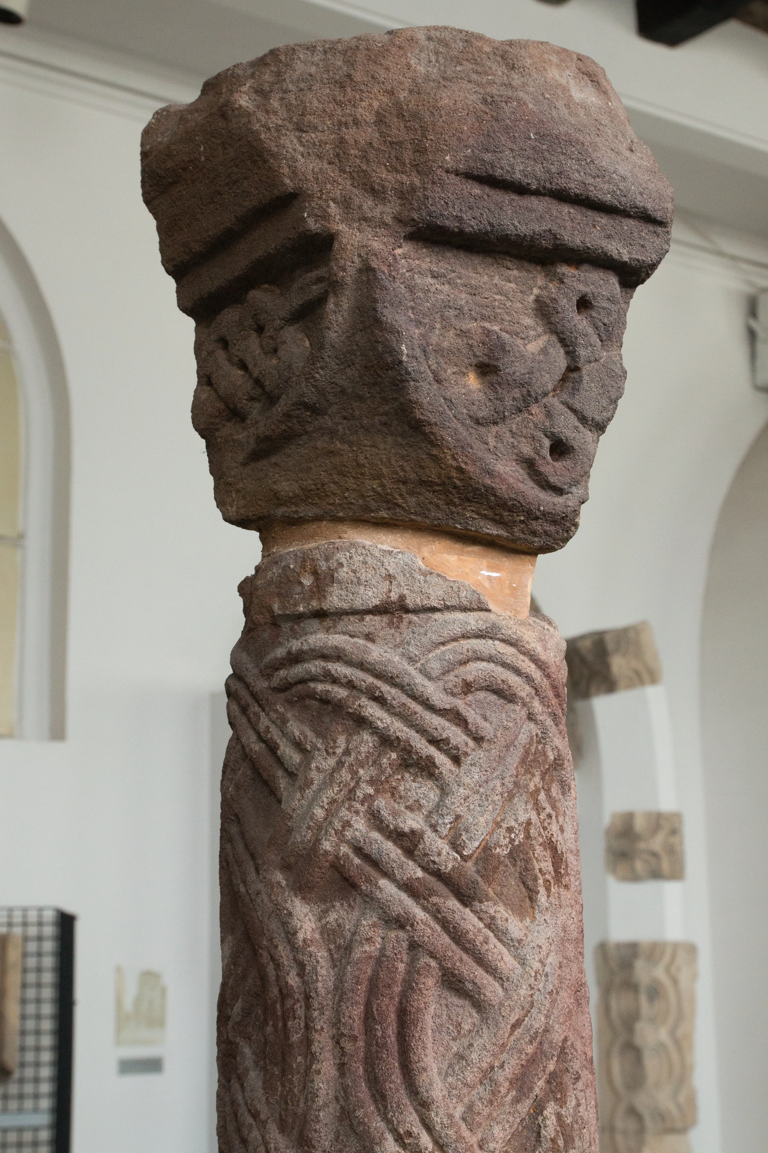 Close-up of a carved stone column capital with detailed patterns and weathered texture