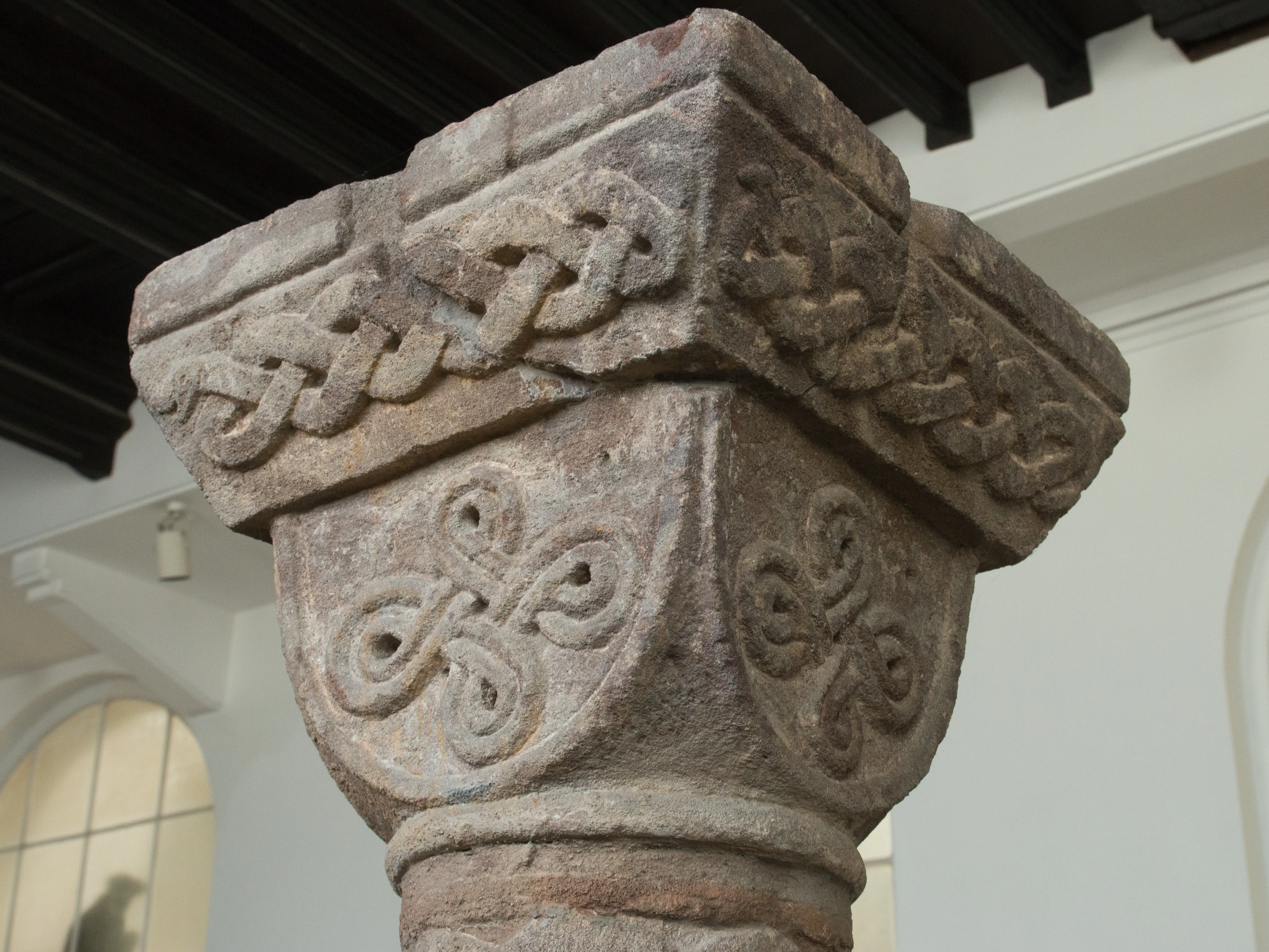 Stone column capital with carved Celtic knot patterns and interlaced designs
