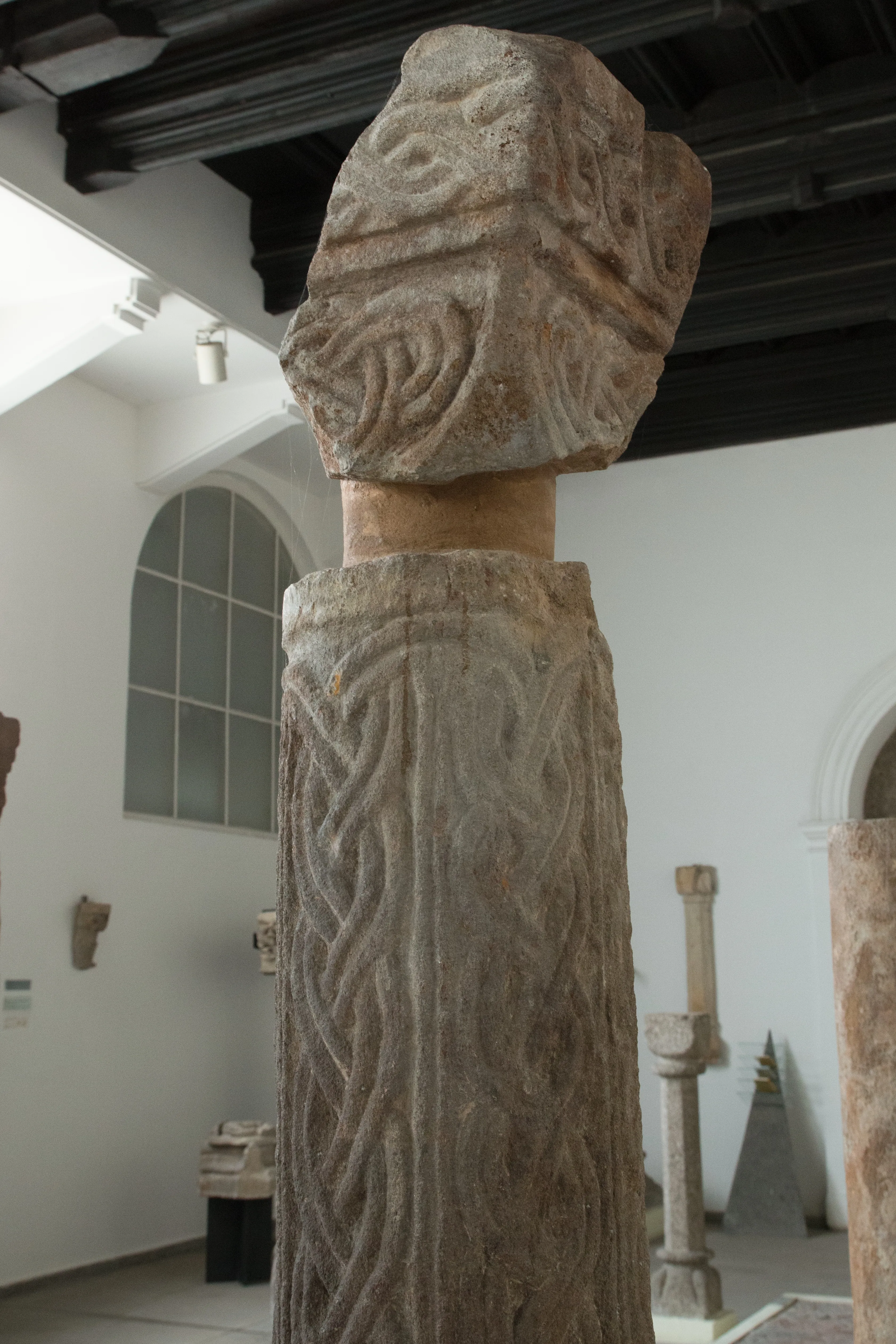 een ingewikkeld stenen beeldhouwwerk van een middeleeuwse pilaar met knoopwerkpatronen in een museumgalerie