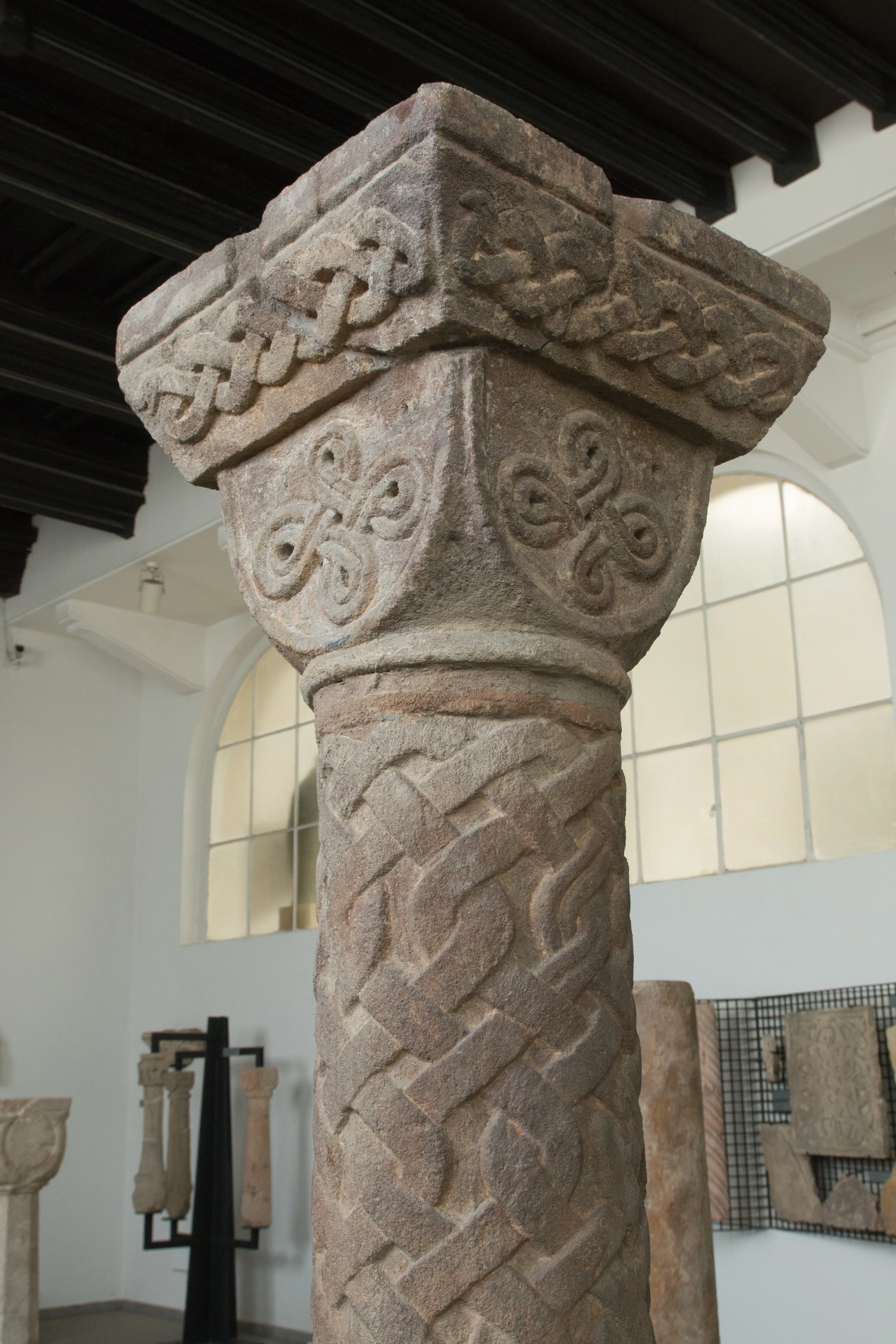 Intricate stone column with Celtic knot carvings in a museum gallery