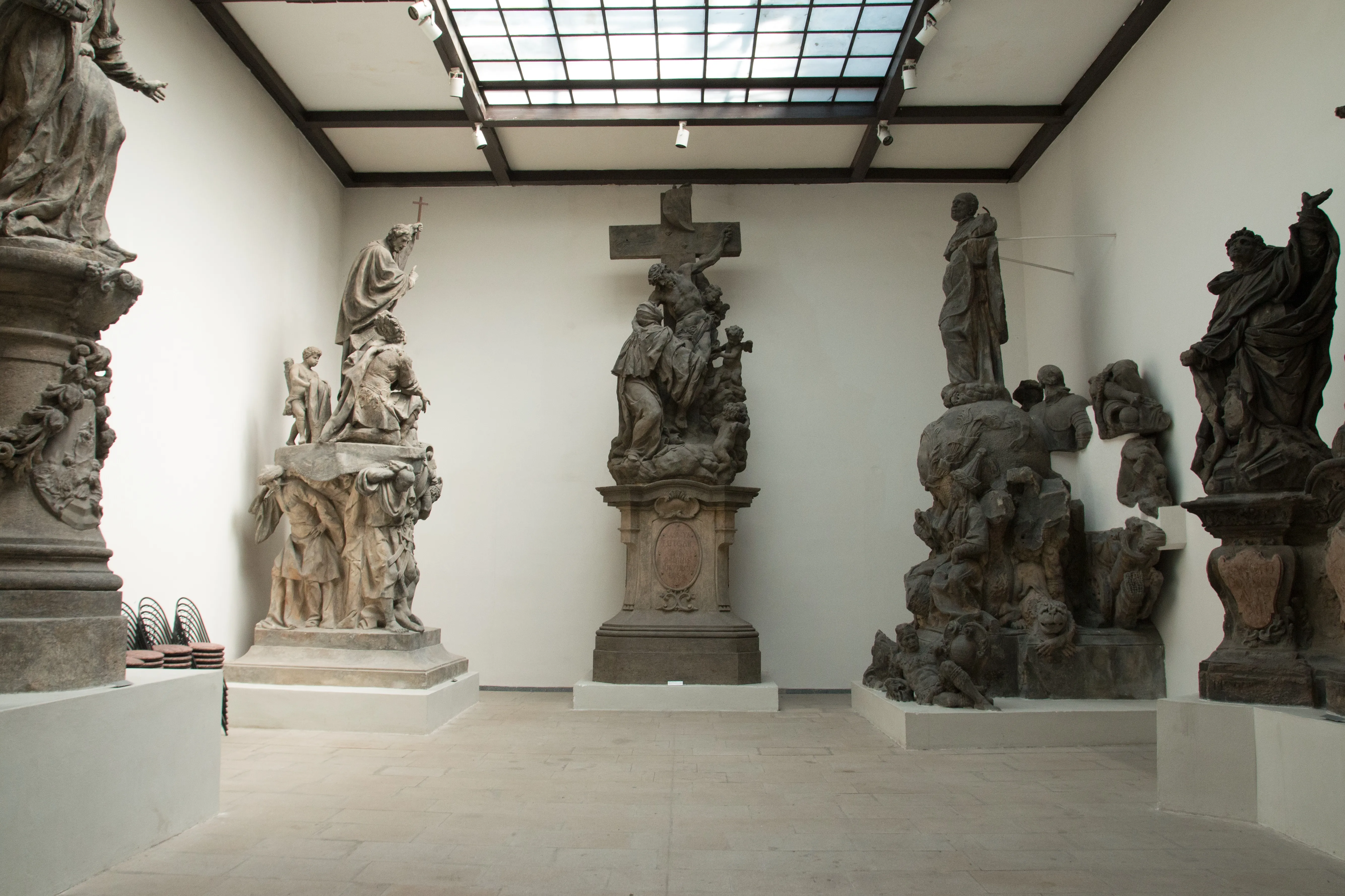 stenen sculpturen op sokkels in een museumgalerij met een daklicht