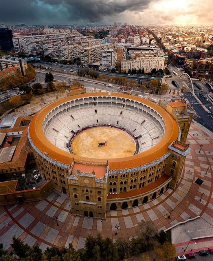 Aerial view of the Plaza de Toros de las Ventas bullring with a circular arena and surrounding urban landscape under a cloudy sky