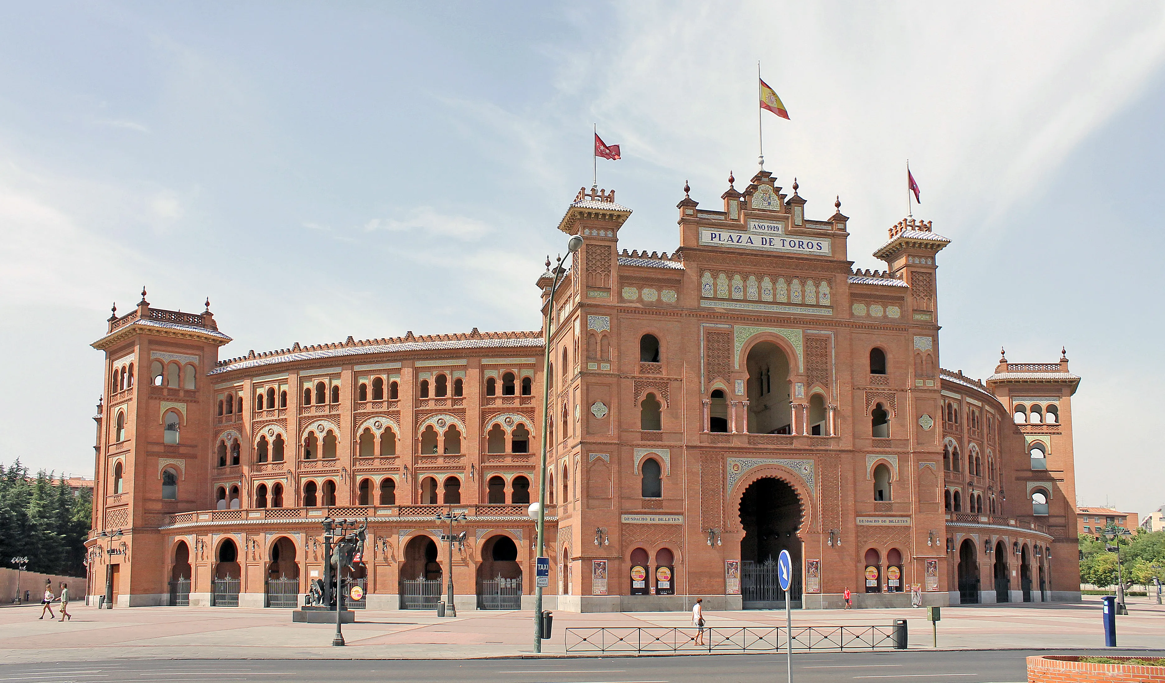 De Plaza de Toros de las Ventas stierenvechtersarena met zijn rode bakstenen gevel, boogvormige ingangen en Spaanse vlaggen bovenop onder een heldere hemel