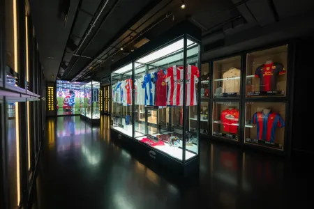 A dark museum hallway with glass display cases containing football jerseys and memorabilia