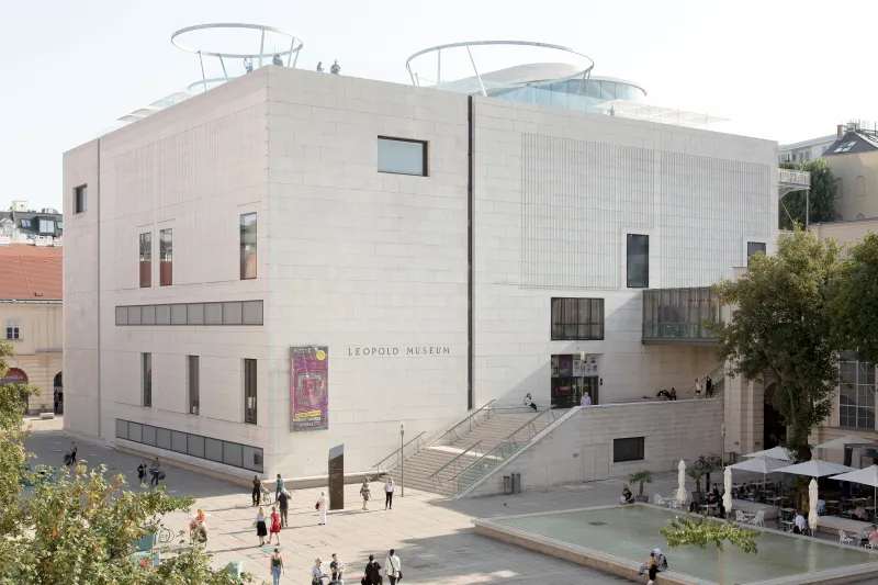 Het Leopold Museum gebouw met een moderne gevel, zitplaatsen buiten en mensen die rondlopen