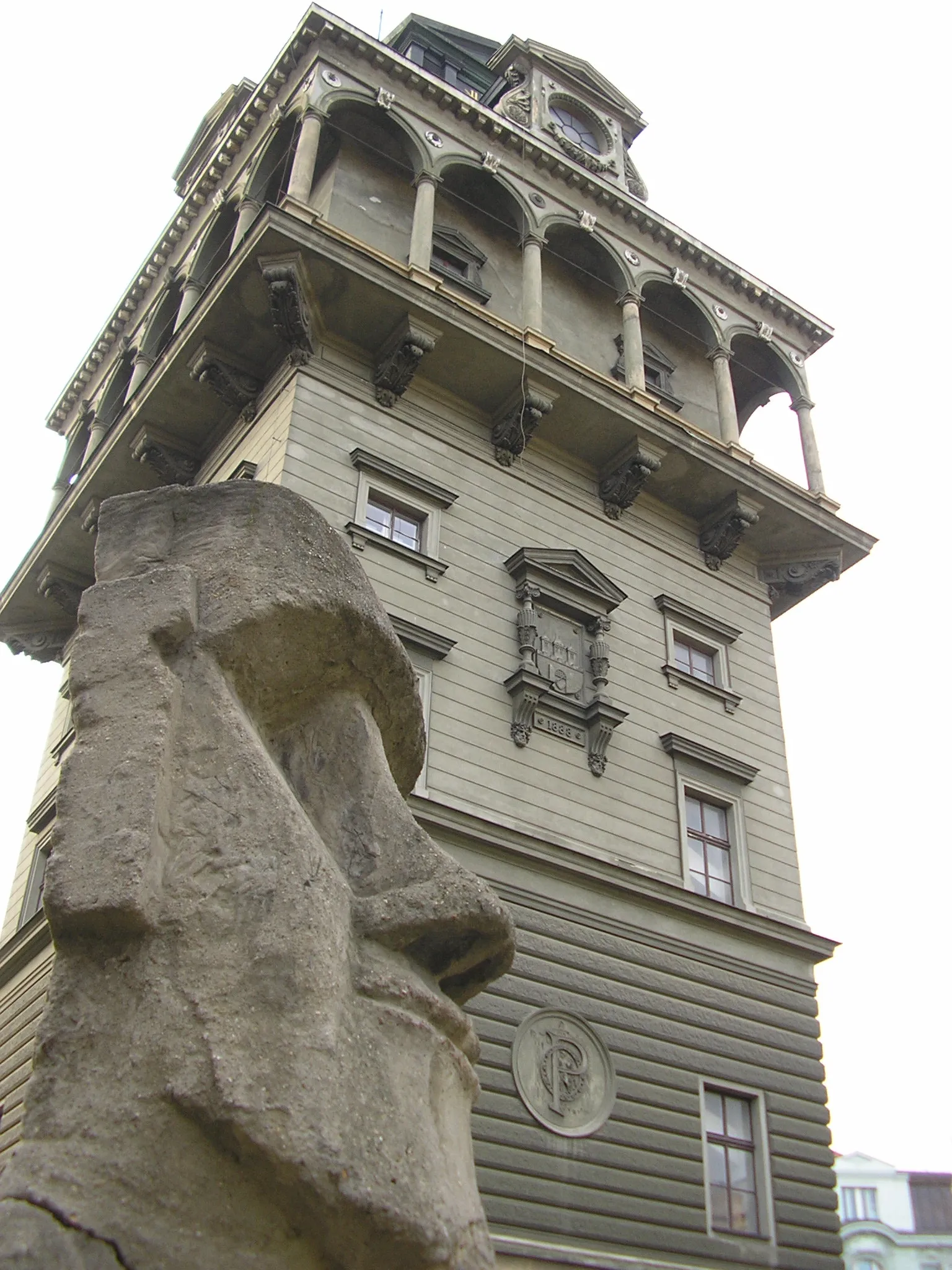 Una alta torre de agua histórica con balcones ornamentados y una escultura de piedra en primer plano