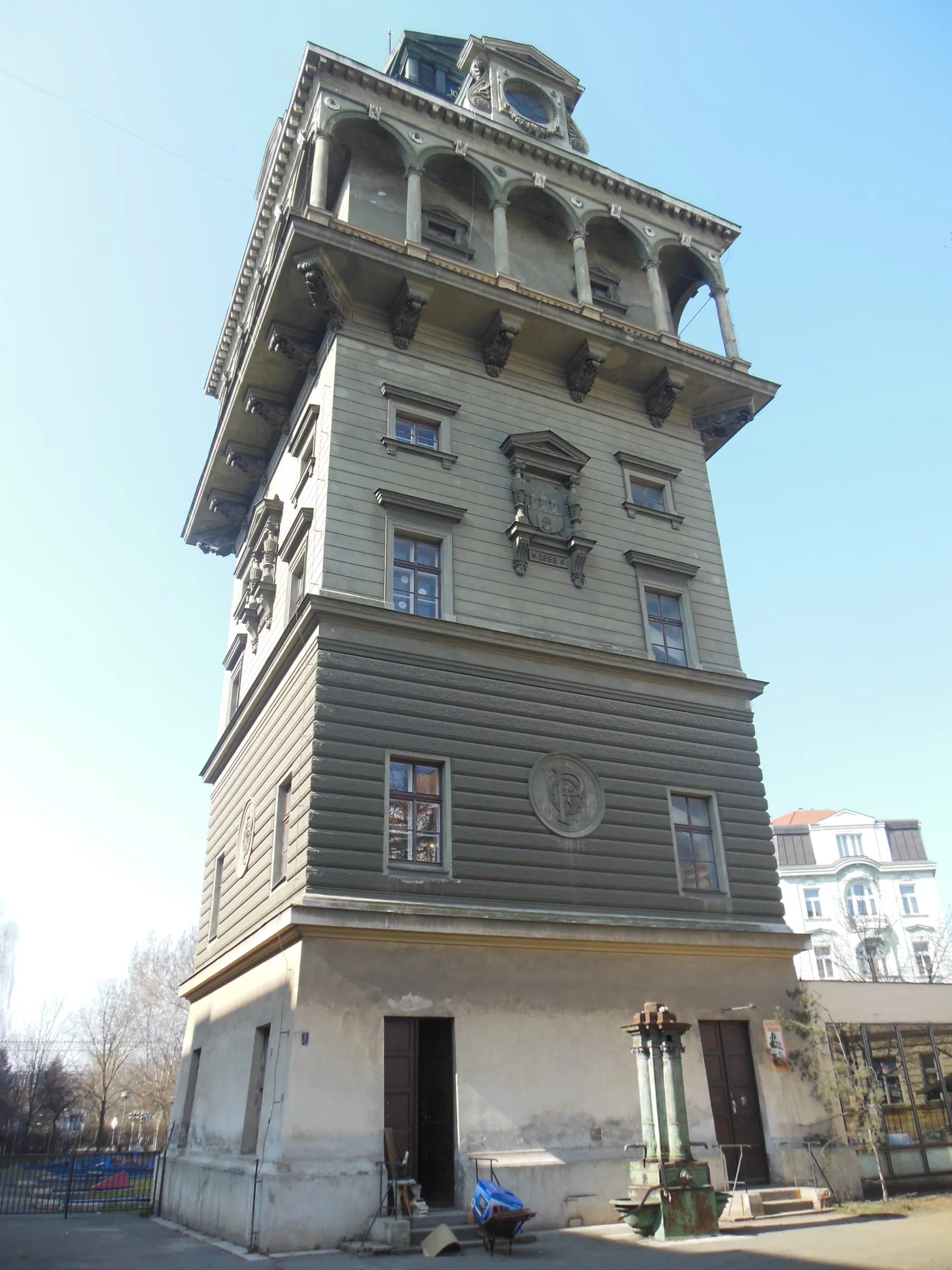Una torre de agua alta e histórica con detalles arquitectónicos ornamentados y ventanas arqueadas bajo un cielo azul claro