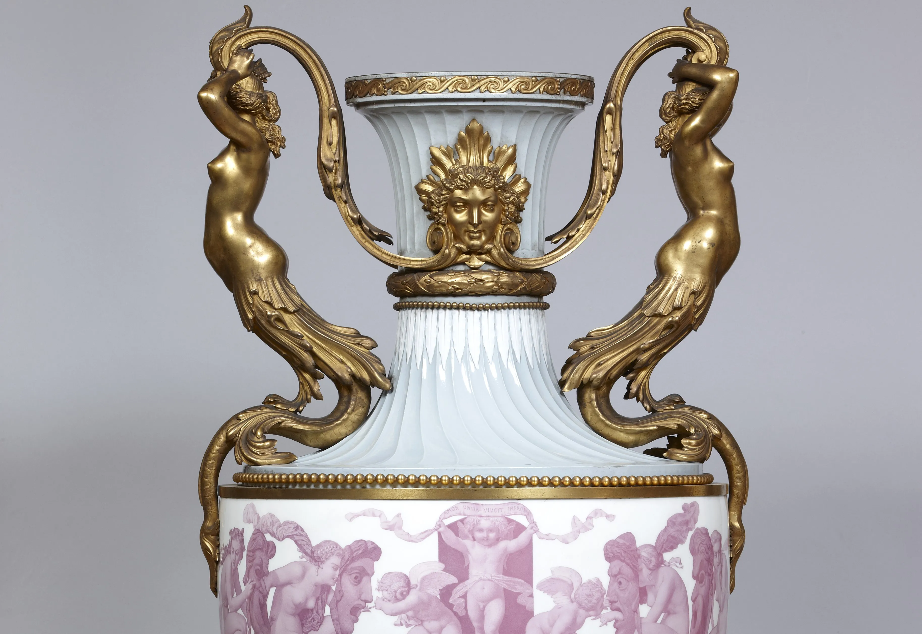 Vaso ornamentado con figuras de bronce dorado y cuerpo de porcelana blanca con escenas en relieve color rosa