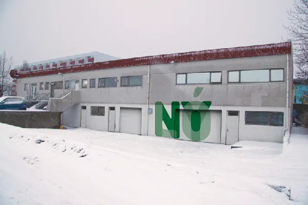 Besneeuwde buitenkant van een gebouw van twee verdiepingen met een rode dakreling en een grote groene NÝ-tekstoverlay