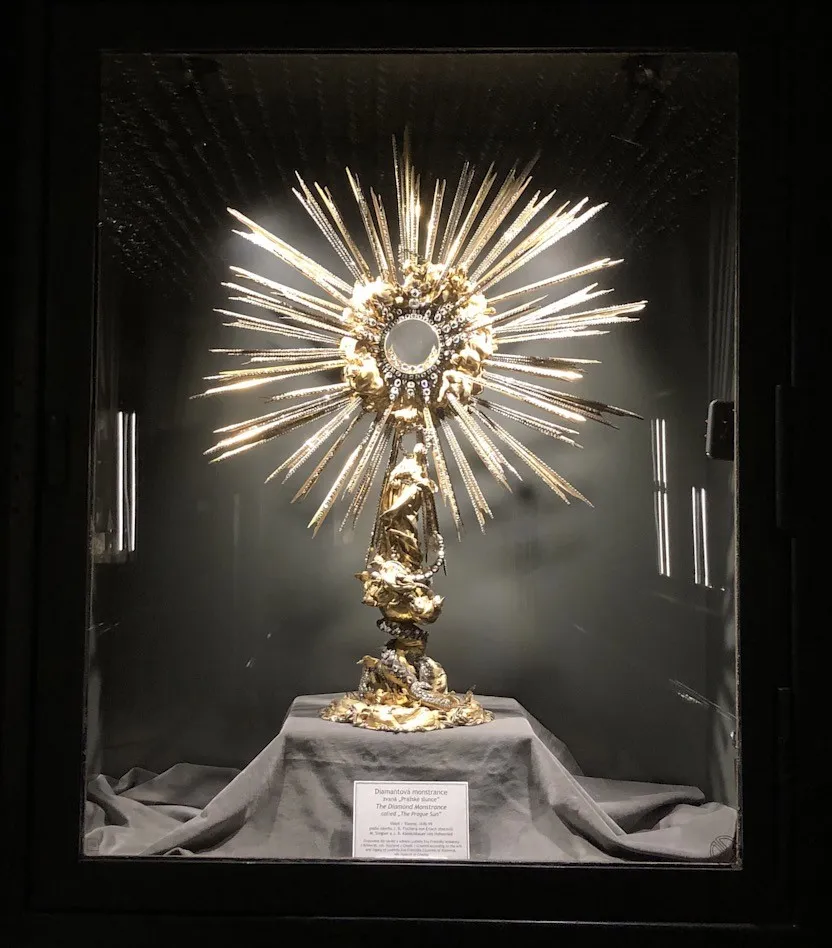 Gouden monstrans met zonnestraalontwerp tentoongesteld in een glazen vitrine