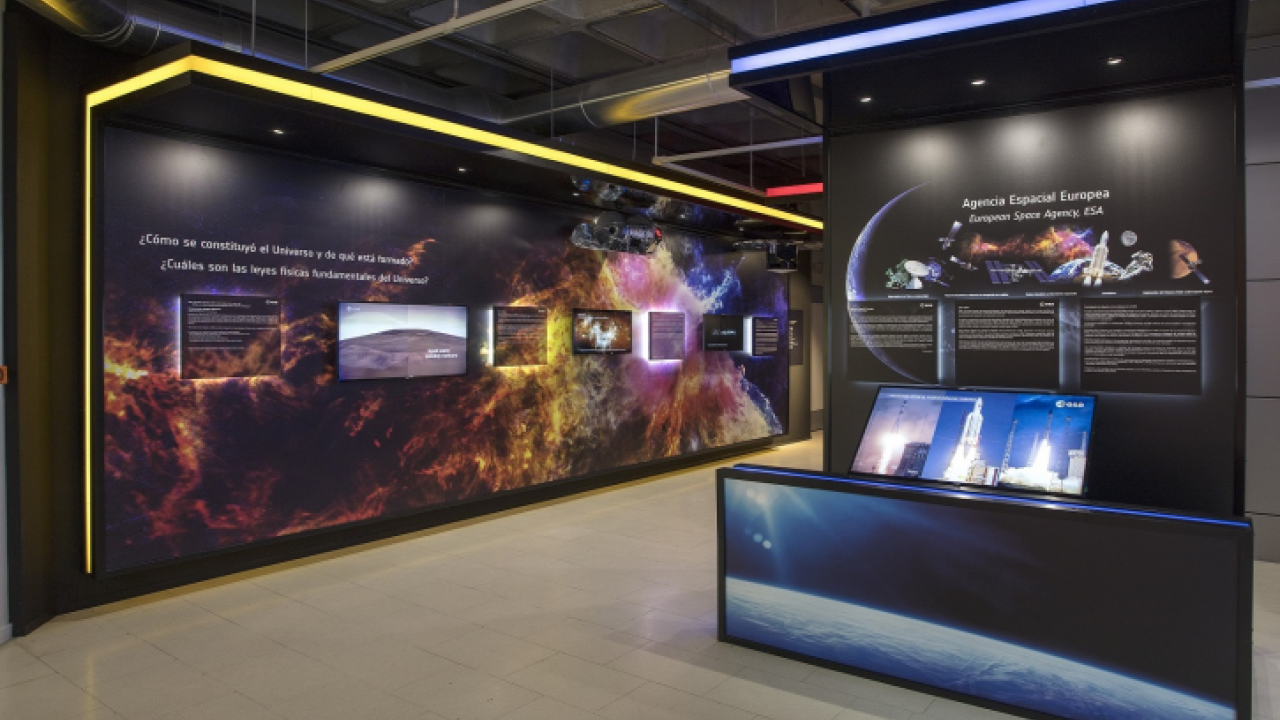 Exhibition hall with a large cosmic mural and interactive displays at the Madrid Planetarium