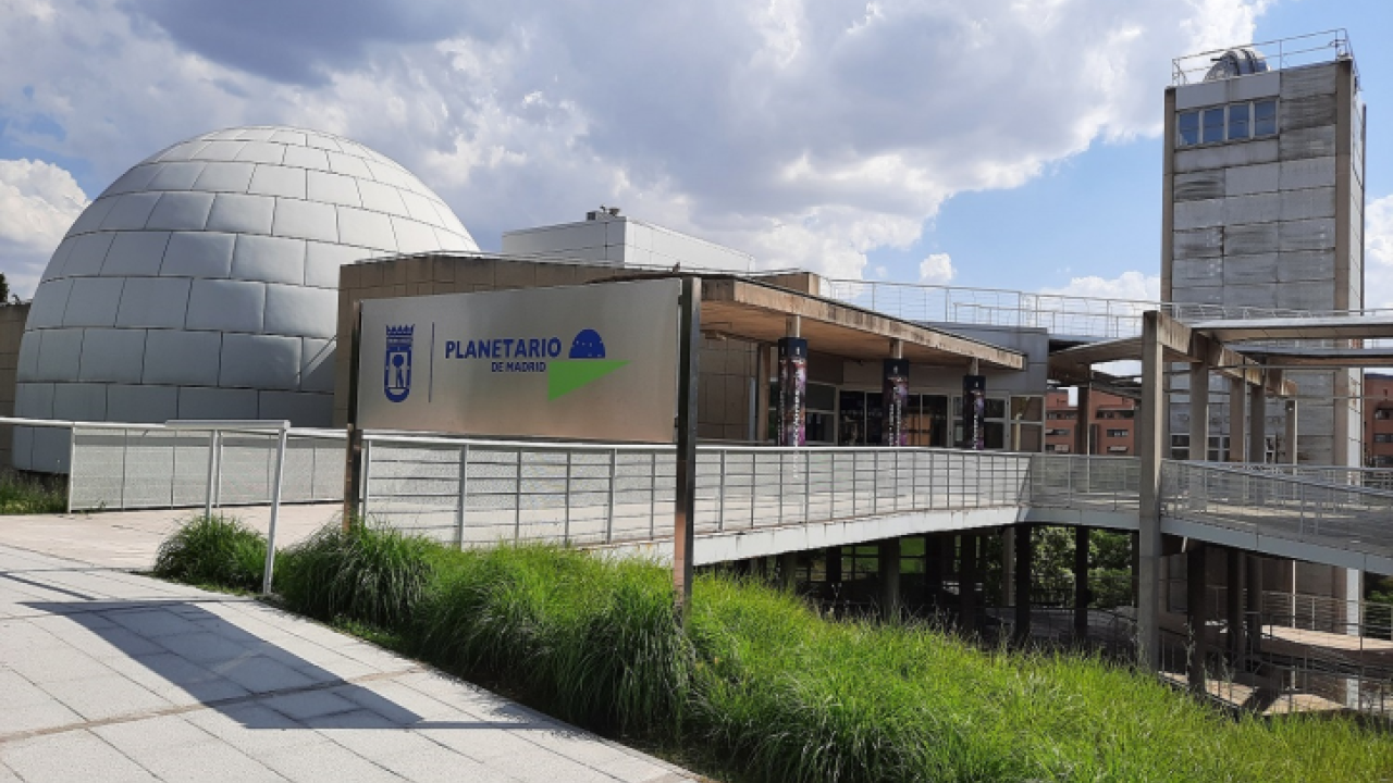 The Madrid Planetarium with a large white dome and a sign reading 'PLANETARIO DE MADRID' on a modern building entrance.