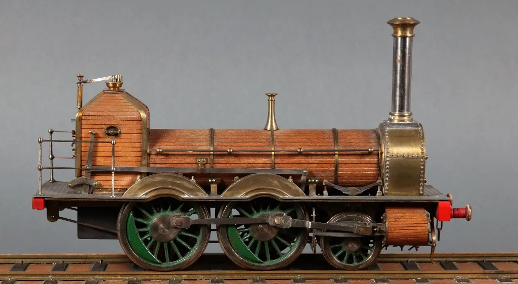 model steam locomotive with wooden body and green wheels on tracks