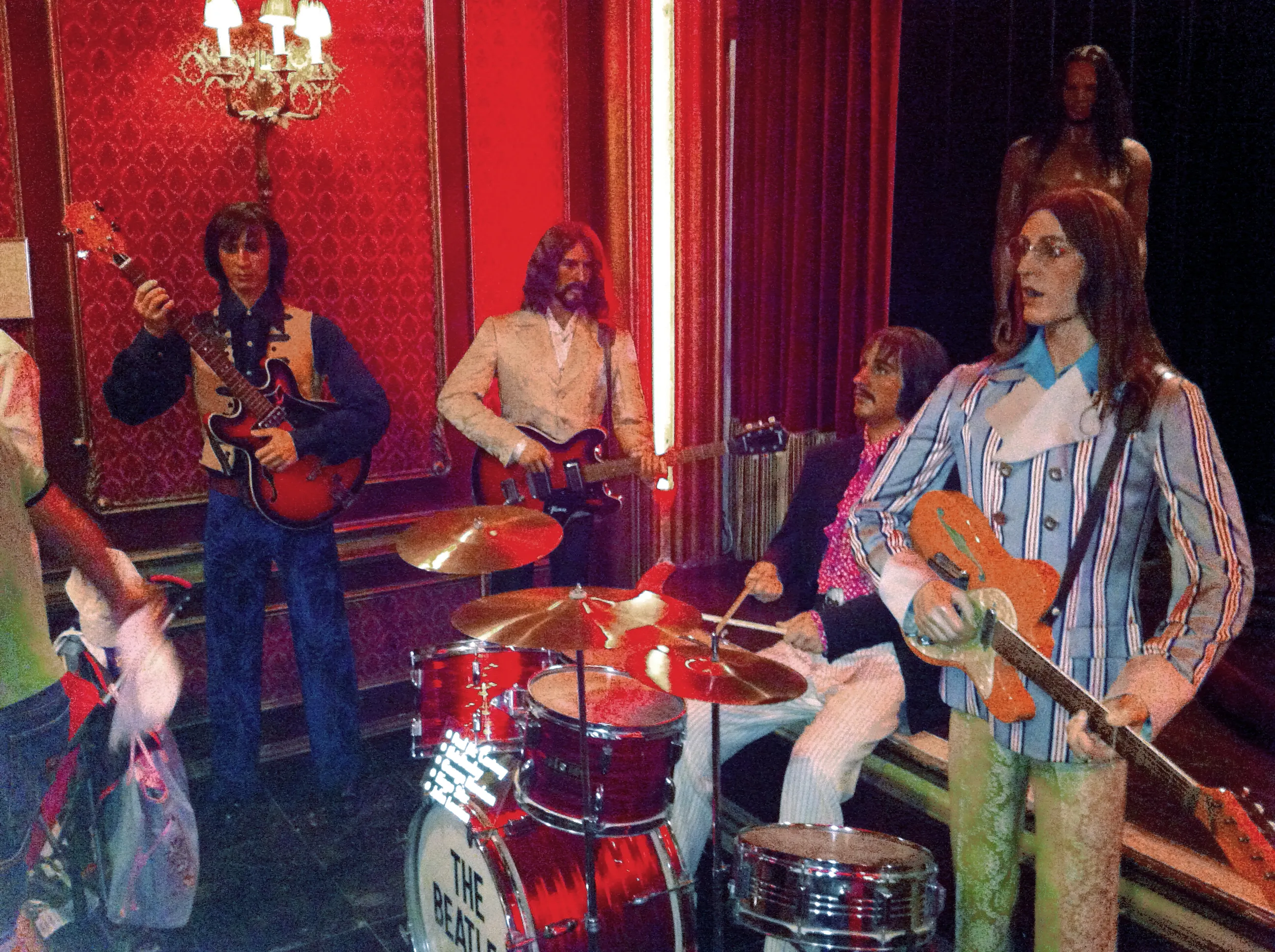 Figuras de cera de The Beatles actuando en el escenario con instrumentos y una batería