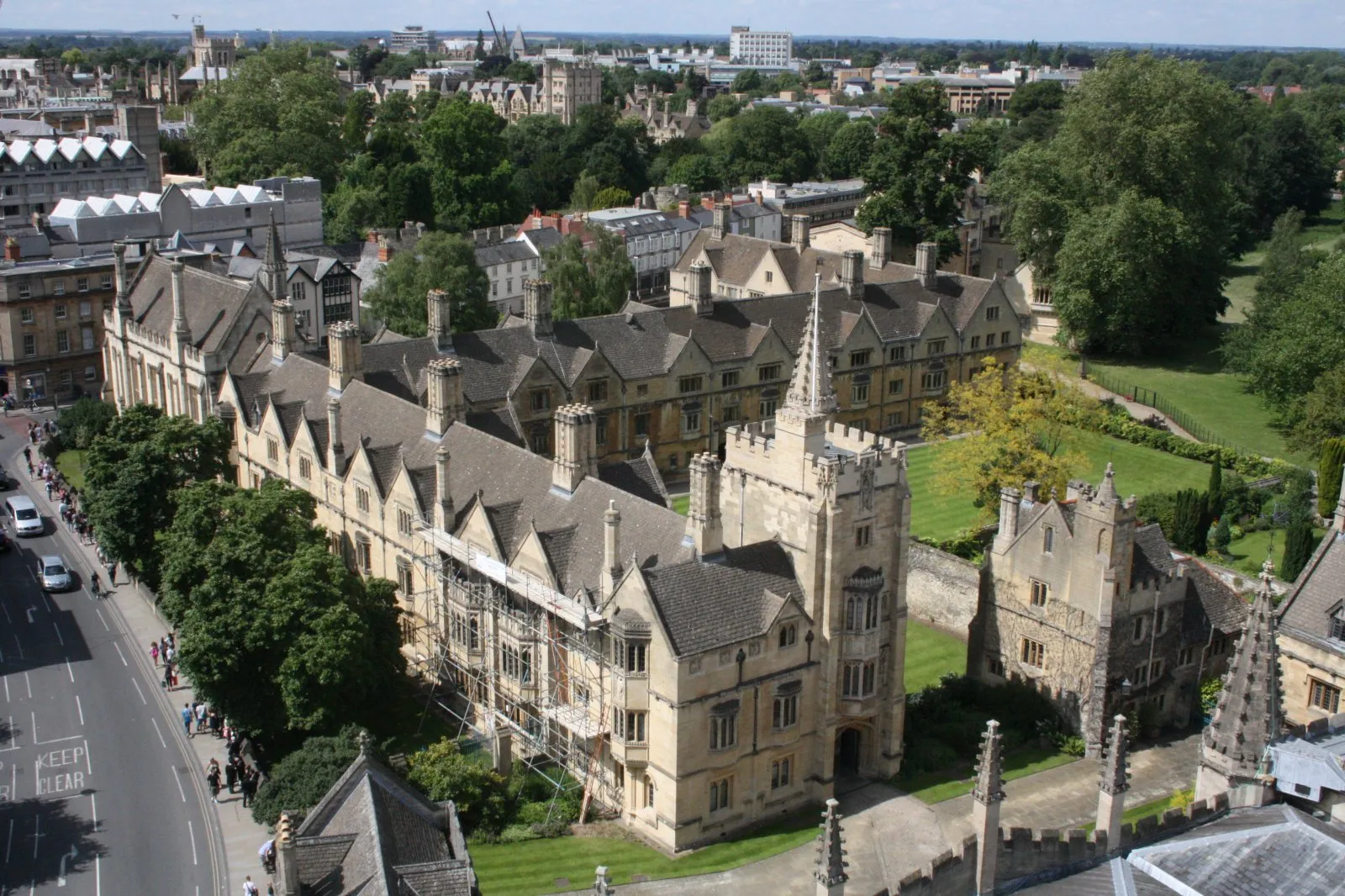 Luchtfoto van de historische gotische stenen gebouwen van Magdalen College met groene gazons en het stadsgezicht van Oxford op de achtergrond