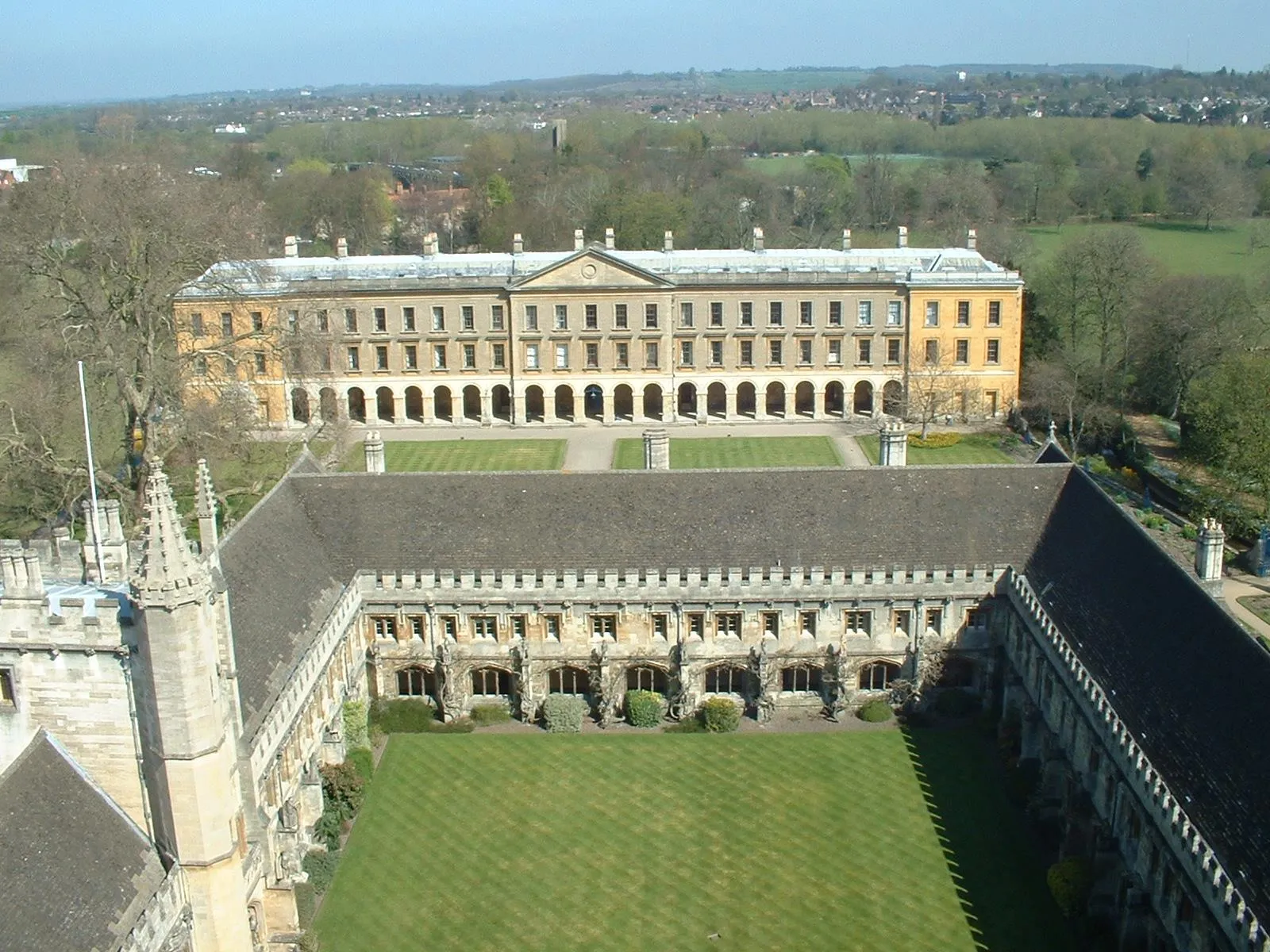 Luchtfoto van Magdalen College met de Great Quad en de kloostergangen op de voorgrond en de lange, klassieke New Buildings op de achtergrond, omringd door groene gazons en bomen.