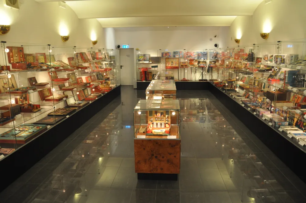 long gallery with glass display cases filled with magic sets and props on both sides