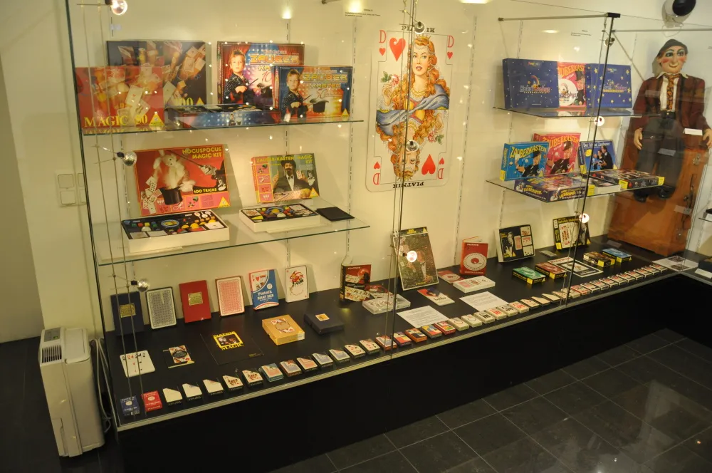 Vitrina de cristal llena de juegos de magia, naipes y carteles en una exposición de museo