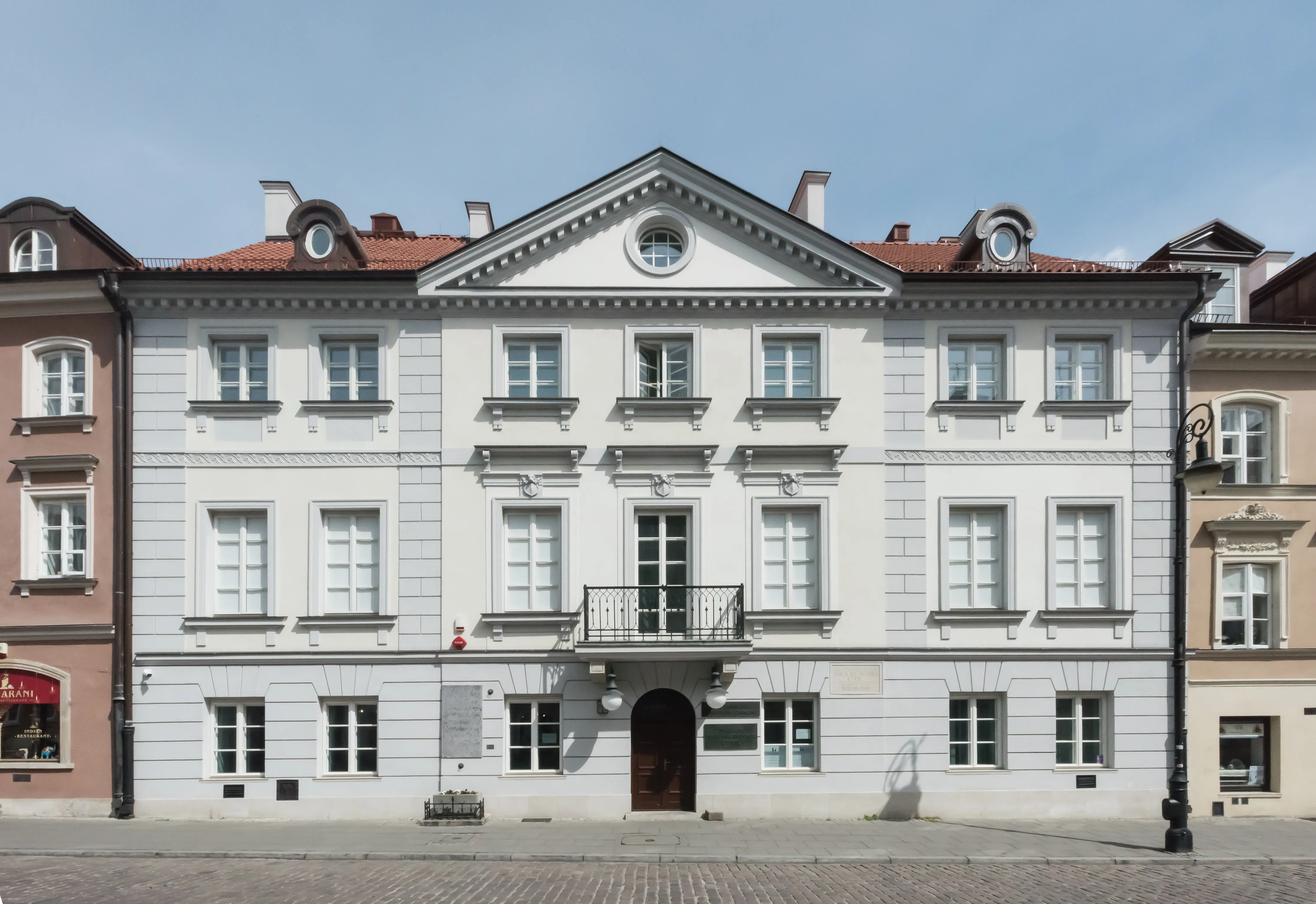 biały klasycystyczny budynek z czerwonym dachem i wieloma oknami