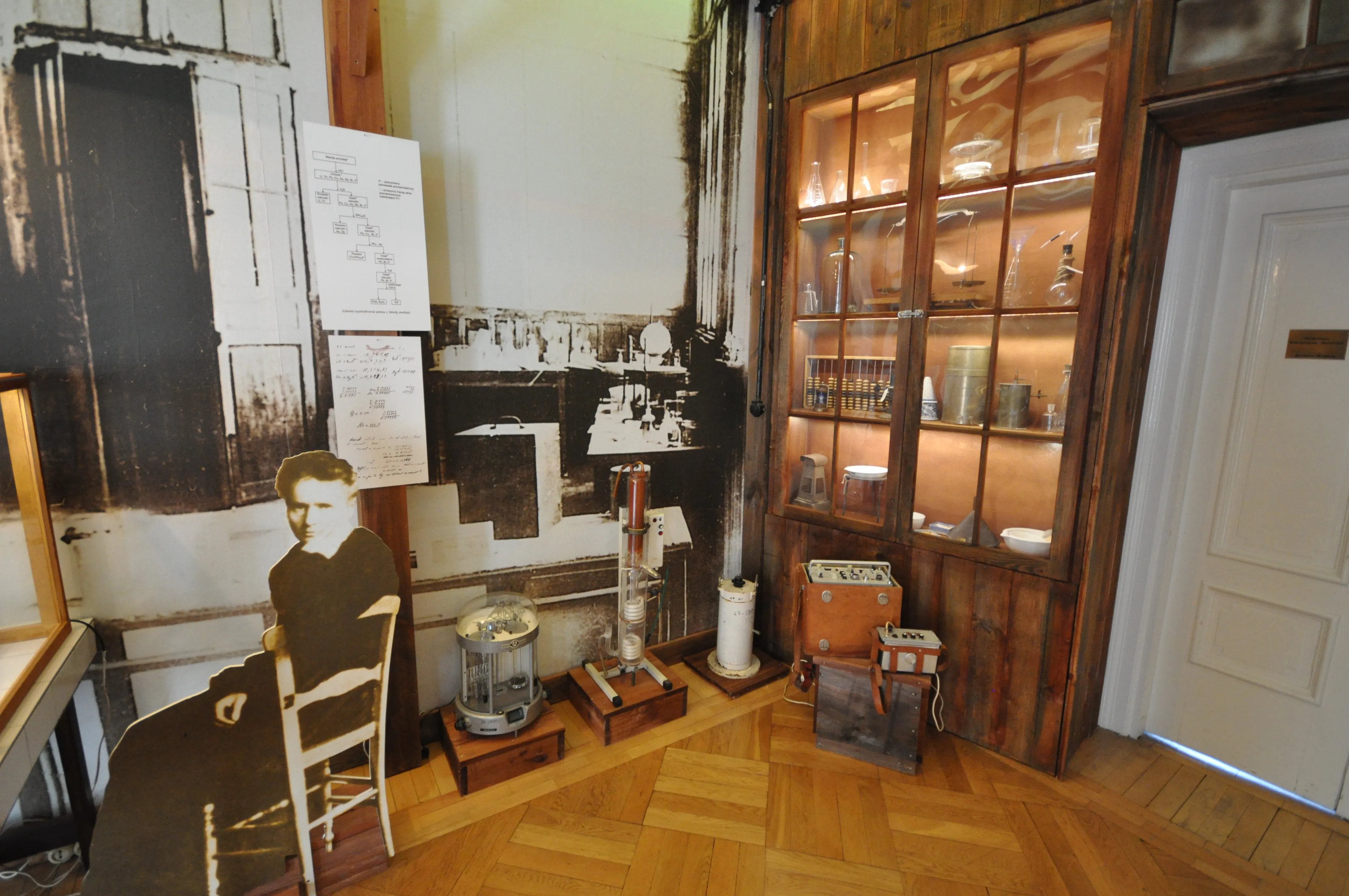 Interior of the Maria Skłodowska-Curie Museum with a cutout of the scientist, scientific instruments, and a display cabinet