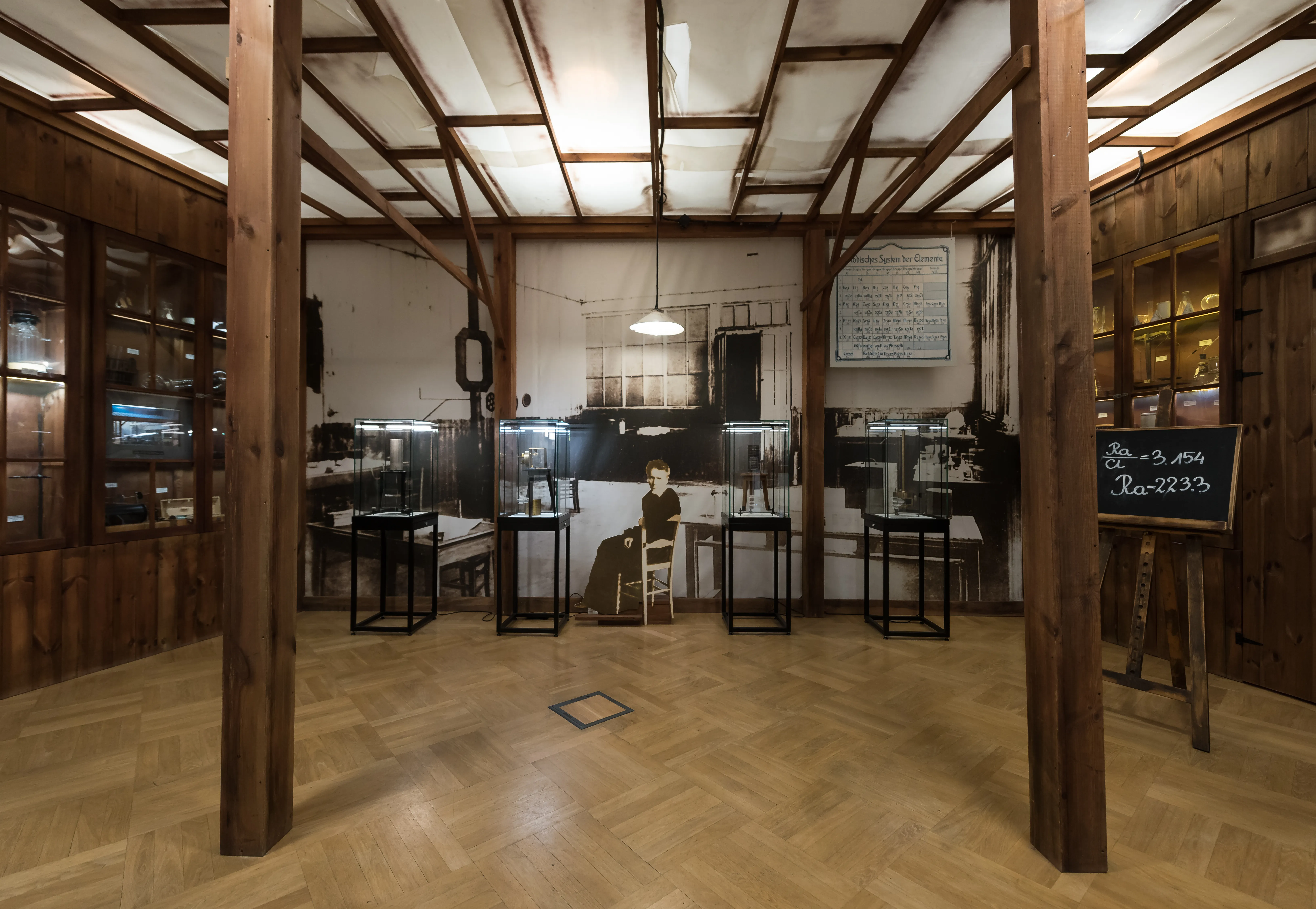 Wnętrze muzeum z drewnianymi belkami, podłogą w jodełkę oraz gablotami zawierającymi instrumenty naukowe i artefakty